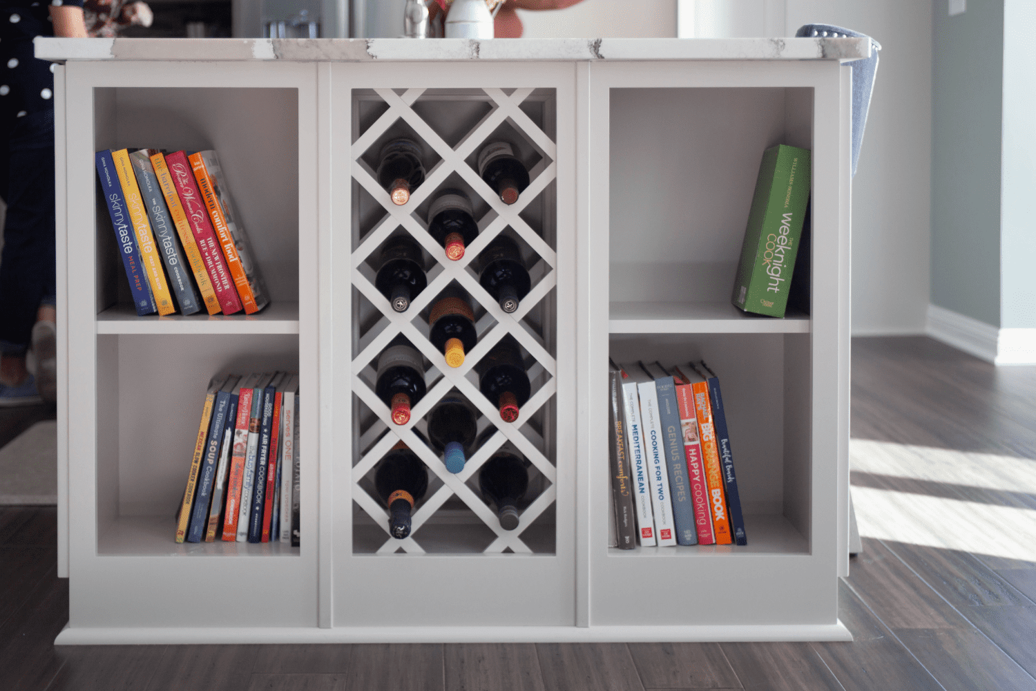 Nicholas Design Build | A kitchen island with a wine rack and books.