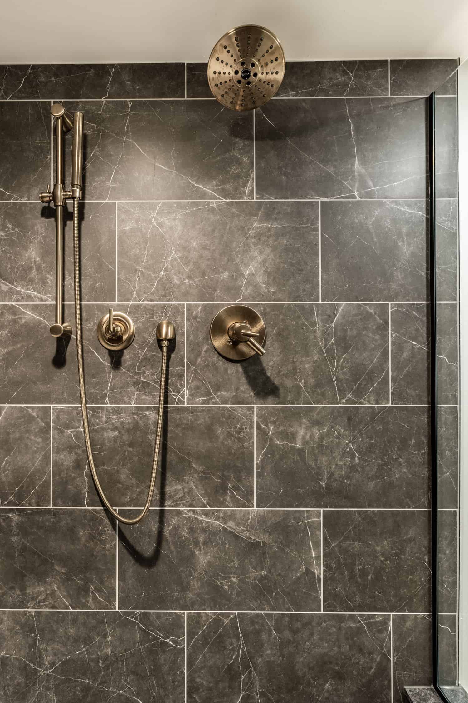 Nicholas Design Build | Remodel a bathroom with black marble tile and brass fixtures.