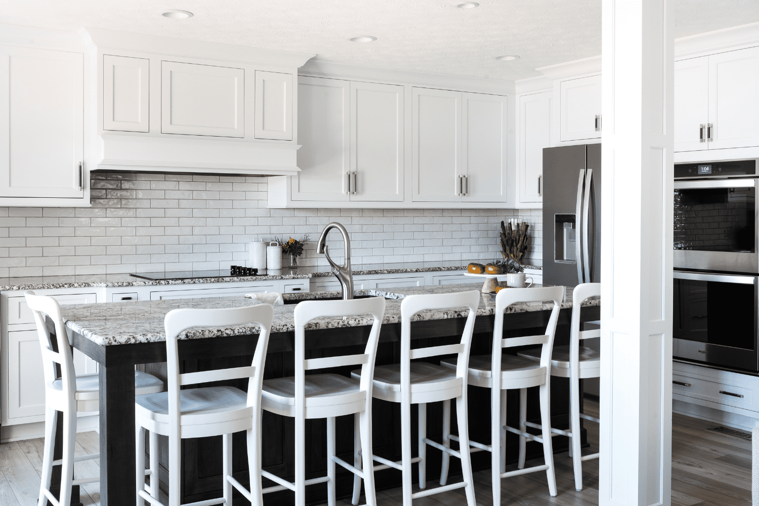 Nicholas Design Build | A kitchen with white cabinets and black stools.