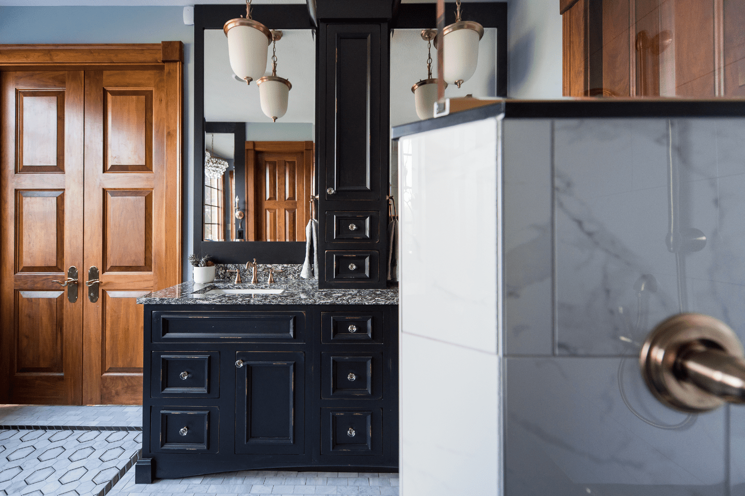Nicholas Design Build | A bathroom with black cabinets and marble counter tops.