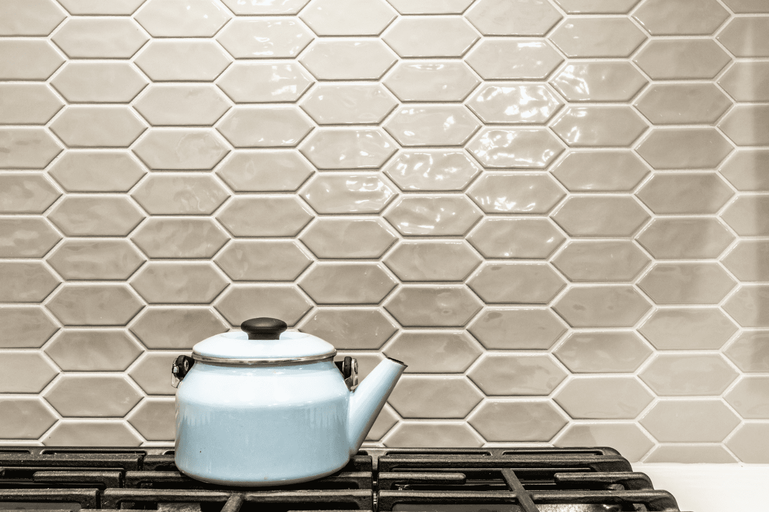 Nicholas Design Build | In a neutral kitchen, a blue teapot sits on top of a stove.