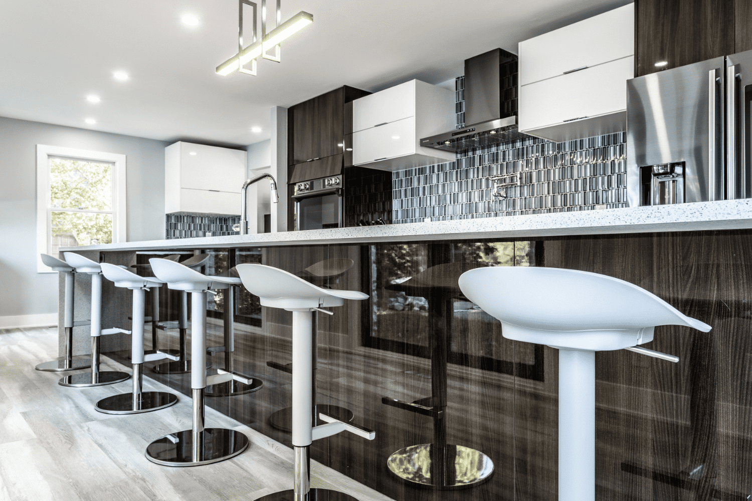 Nicholas Design Build | A modern kitchen with white counter tops and black bar stools.