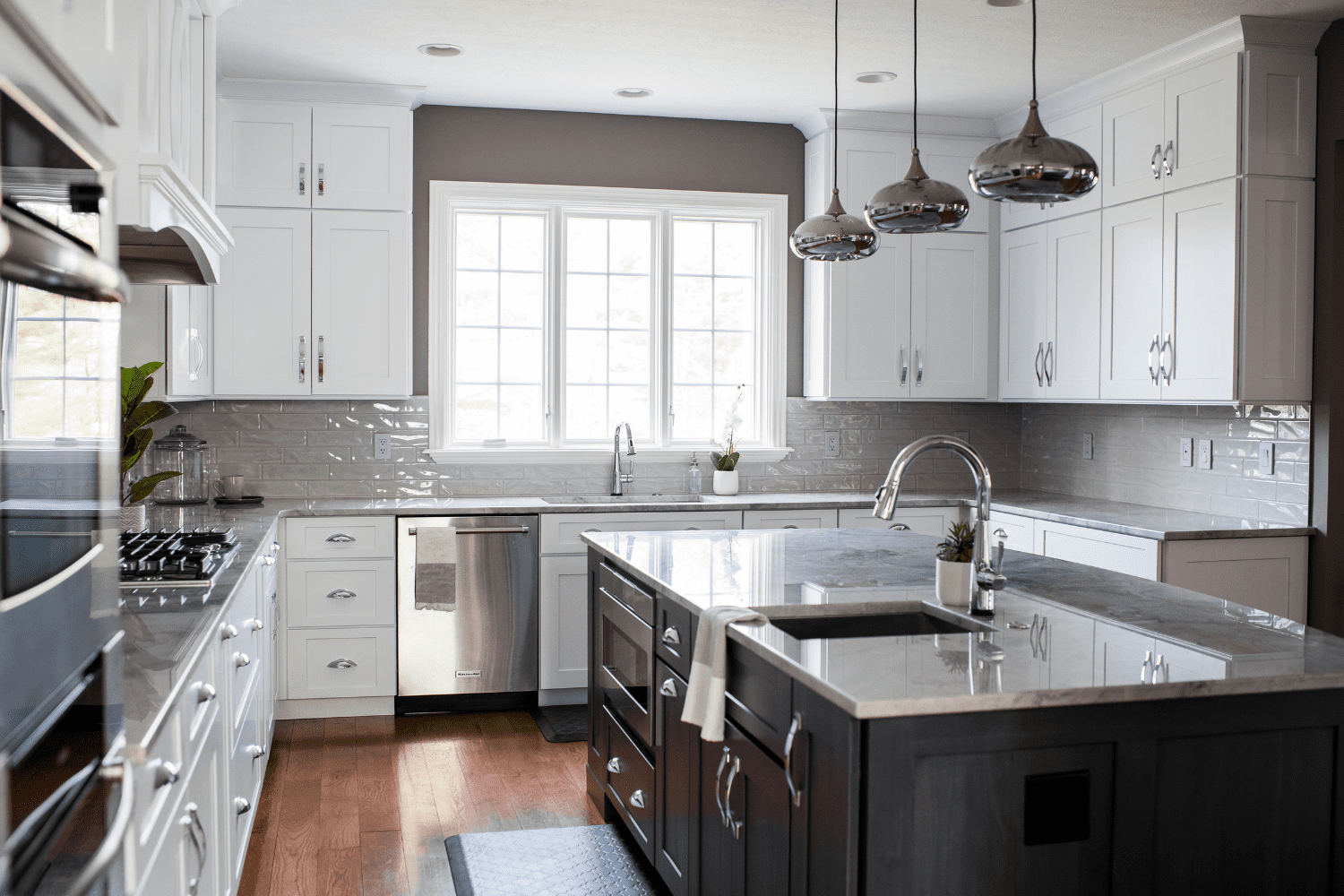Nicholas Design Build | A kitchen with white cabinets and black counter tops.
