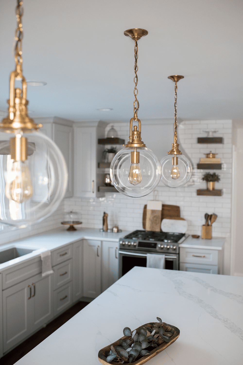 Nicholas Design Build | A neutral kitchen with a marble counter top and glass pendant lights.