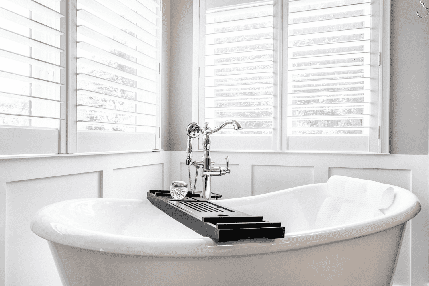Nicholas Design Build | Master bath remodel: A stunning black and white photo capturing a beautifully renovated bathtub with charming shutters.