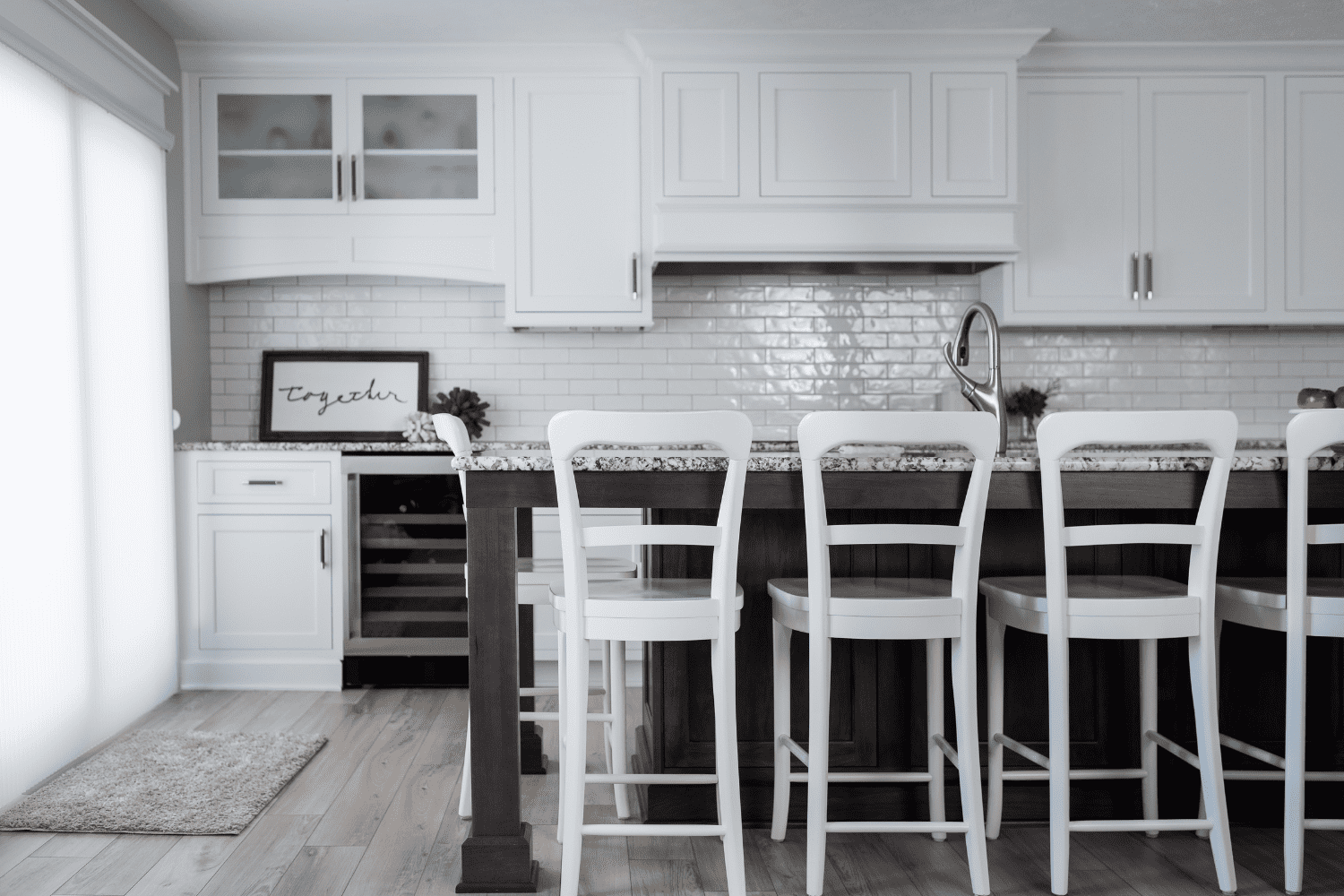 Nicholas Design Build | A black and white photo of a kitchen with white stools.