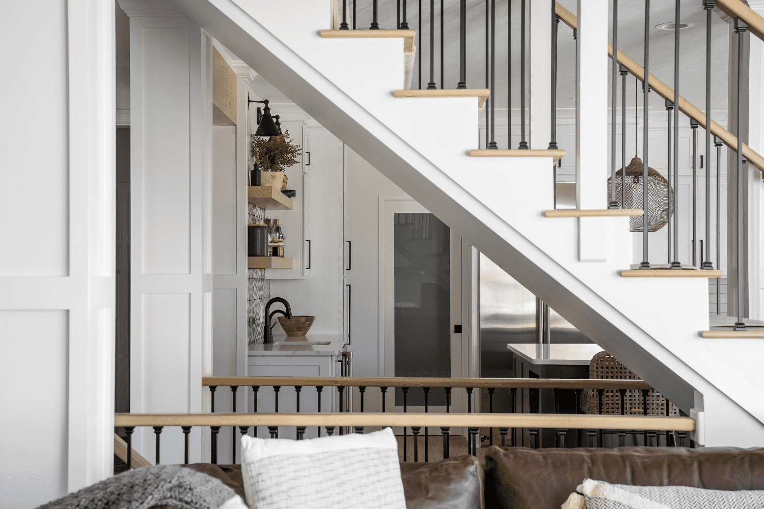 Nicholas Design Build | A white staircase with black railings in a living room.