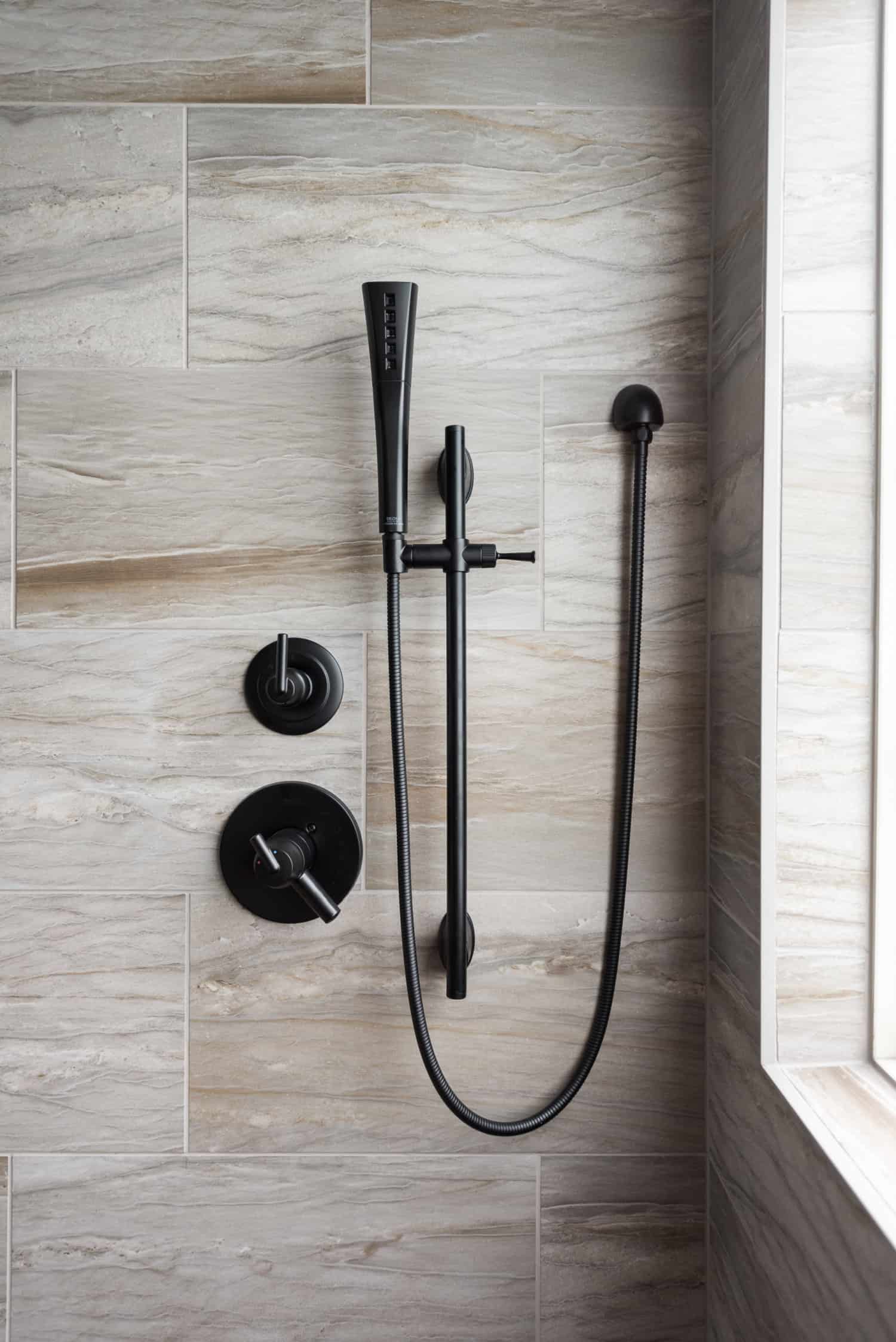 Nicholas Design Build | A modern bathroom with a black shower head and hand shower.