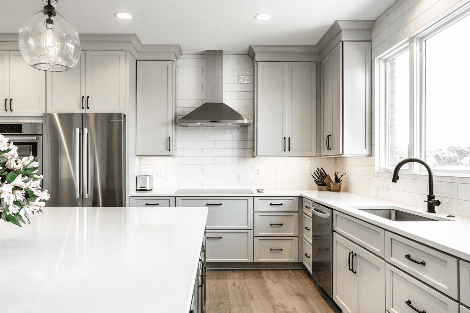 Nicholas Design Build | A kitchen with gray cabinets and white counter tops.