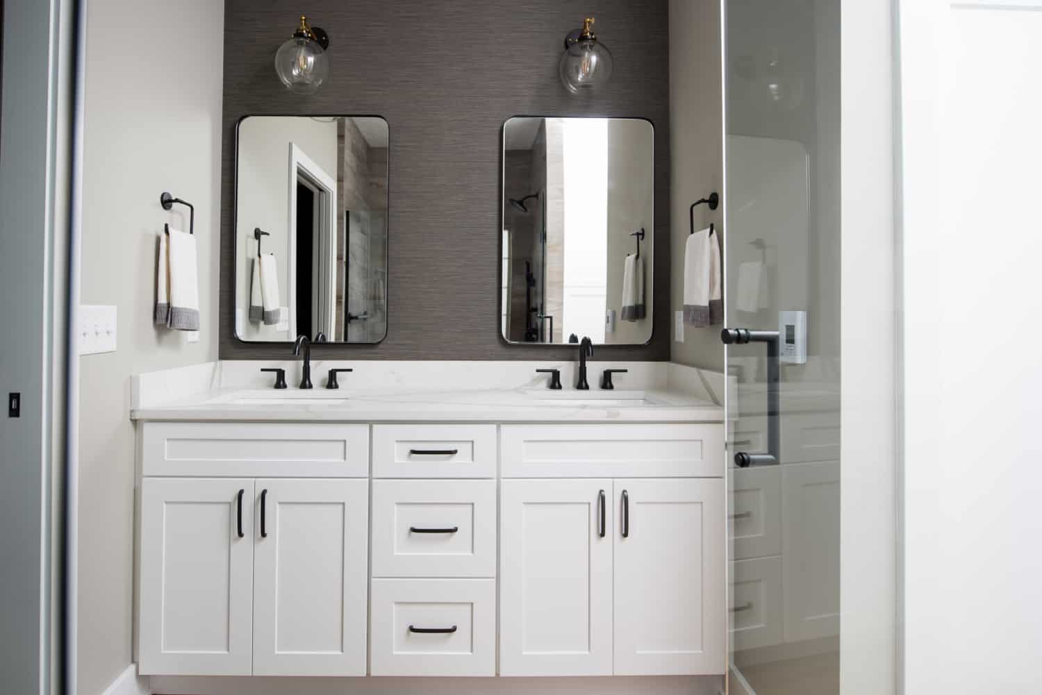 Nicholas Design Build | A modern white bathroom with two sinks and mirrors.