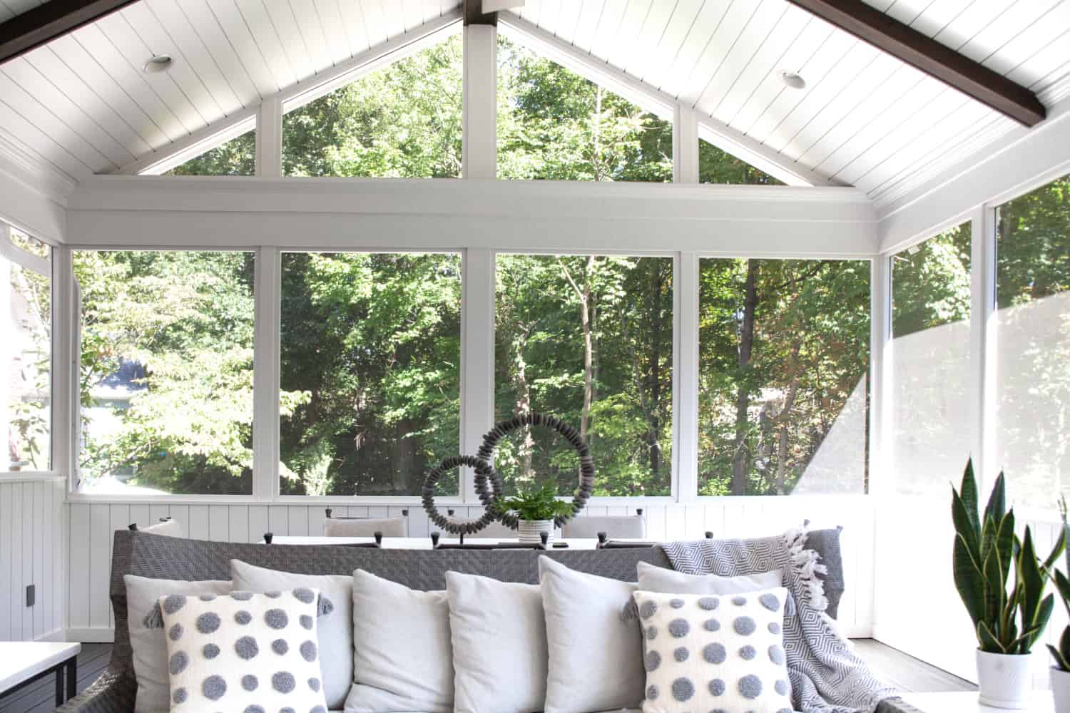 Nicholas Design Build | A screened in porch with a gray couch and white pillows.