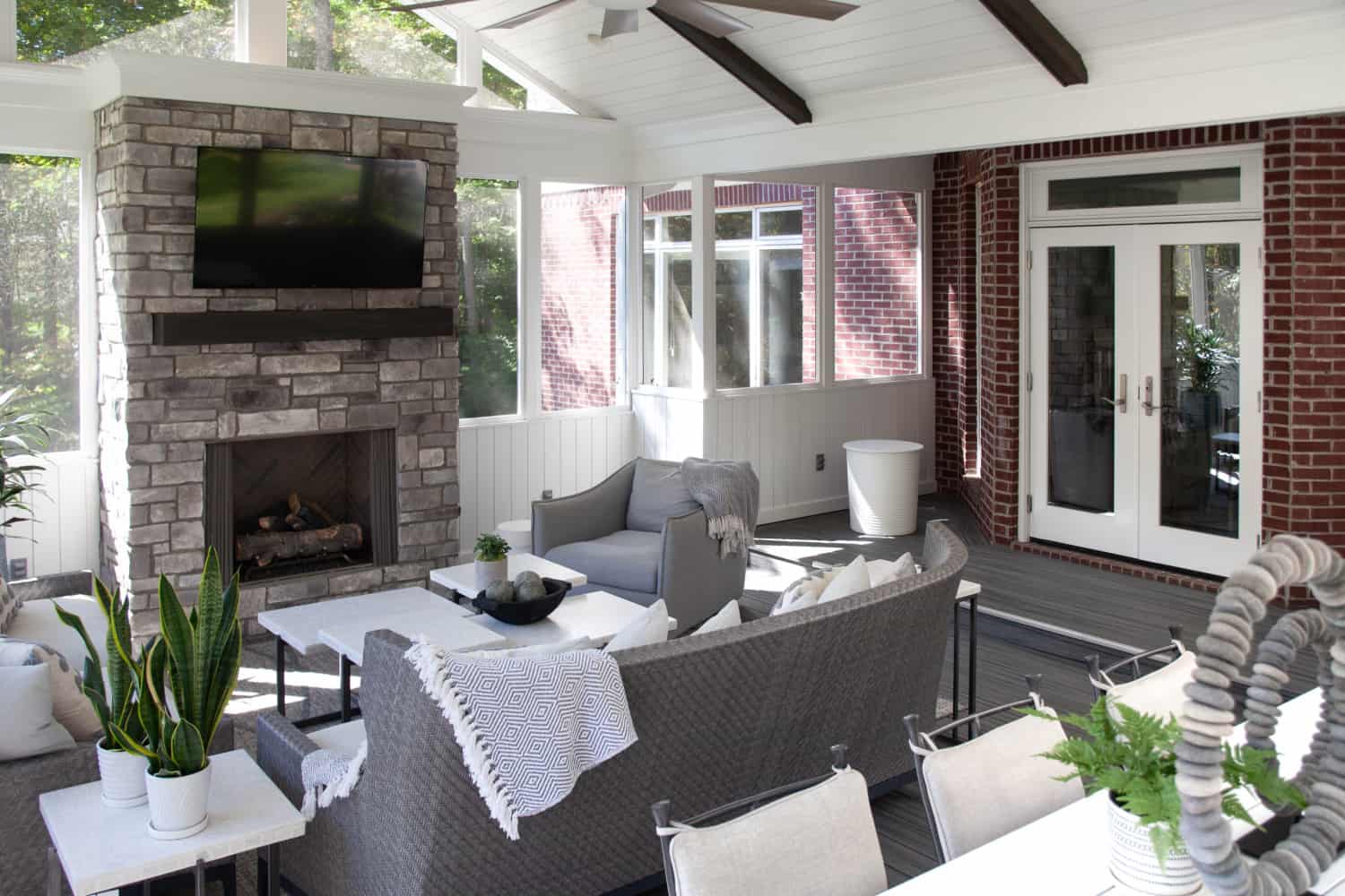 Nicholas Design Build | A screened in porch with a fireplace and tv.