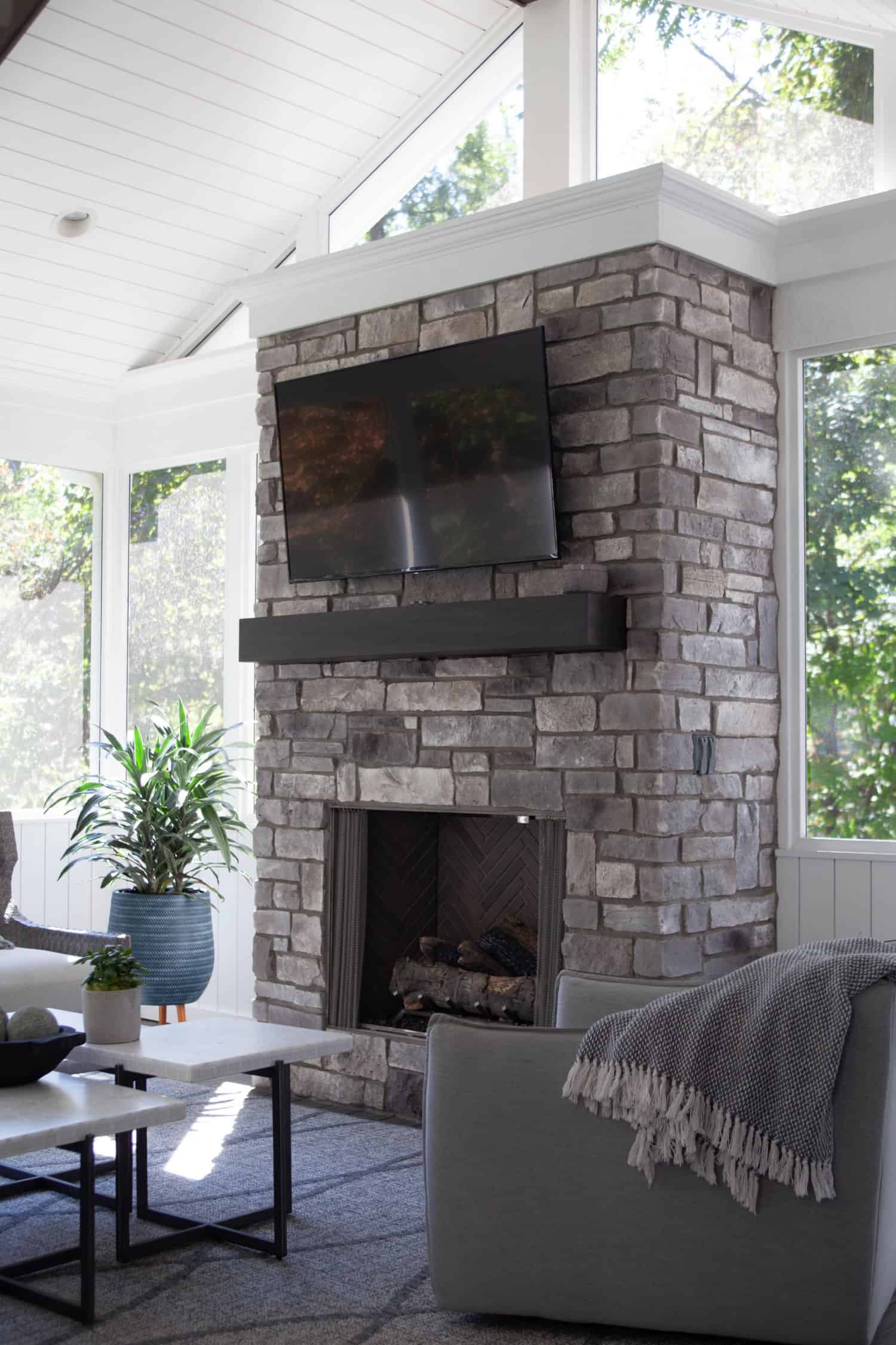 Nicholas Design Build | A living room with a stone fireplace and tv.
