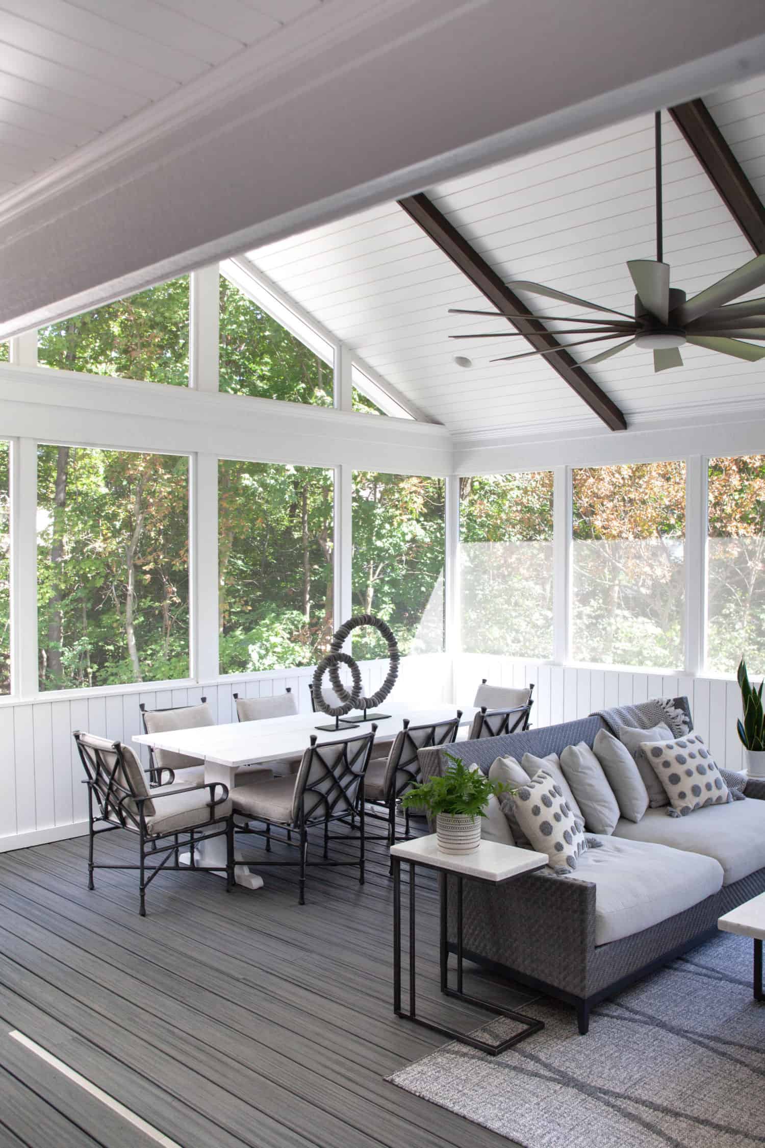 Nicholas Design Build | A screened in porch with white furniture and a ceiling fan.