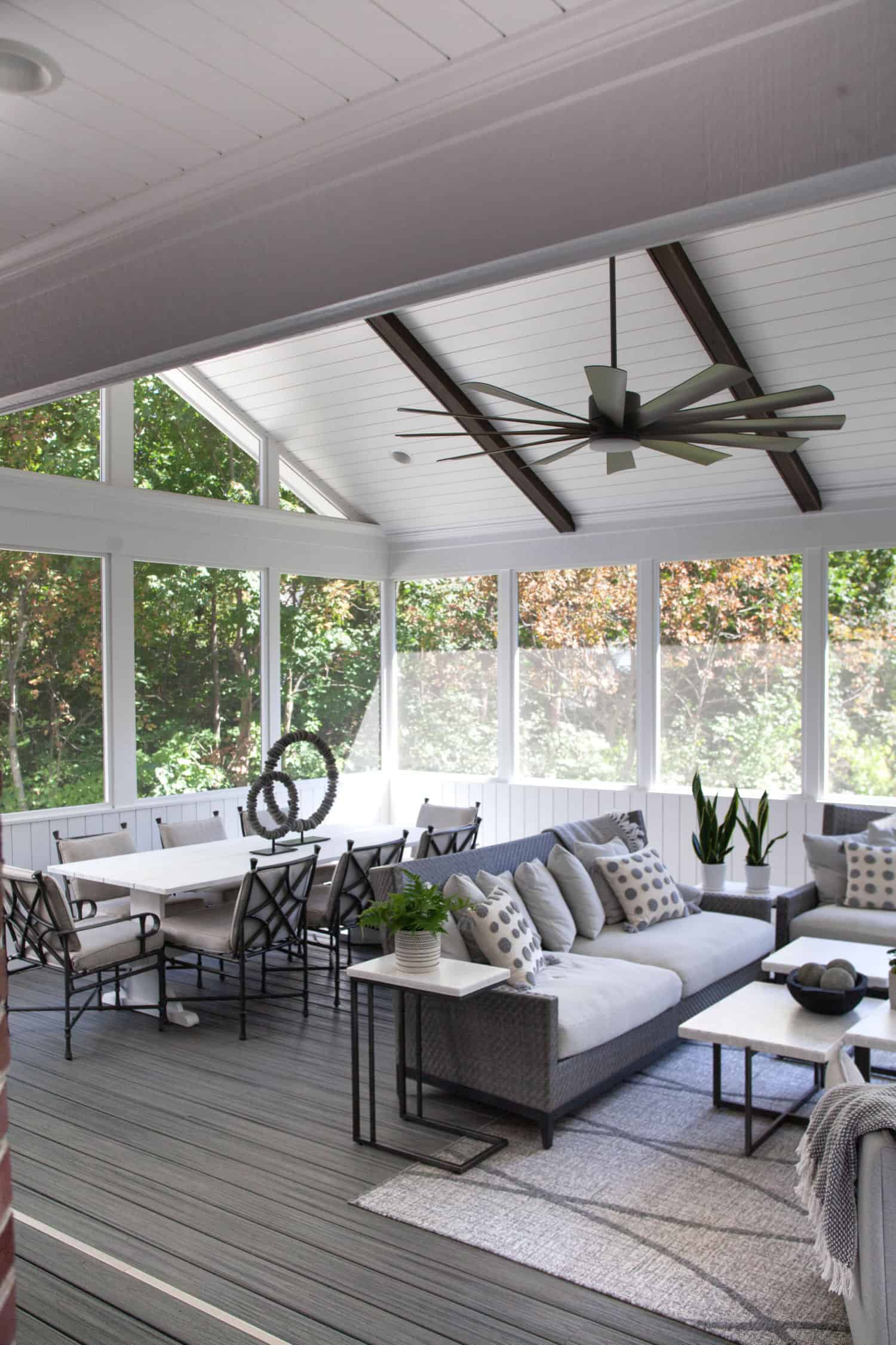Nicholas Design Build | A screened in porch with white furniture and a ceiling fan.