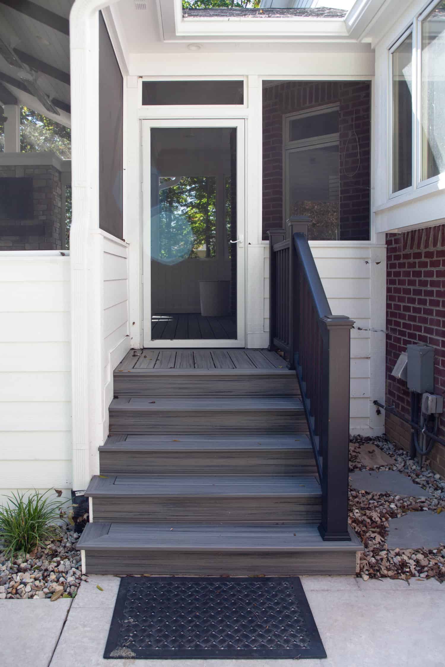 Nicholas Design Build | A screened in porch with steps leading up to a house.