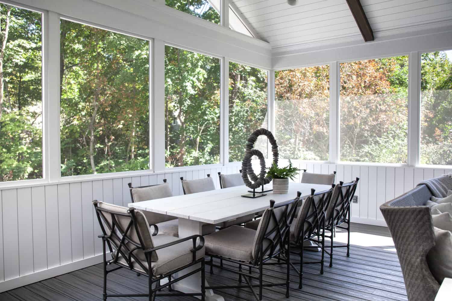 Nicholas Design Build | A screened in porch with a table and chairs.
