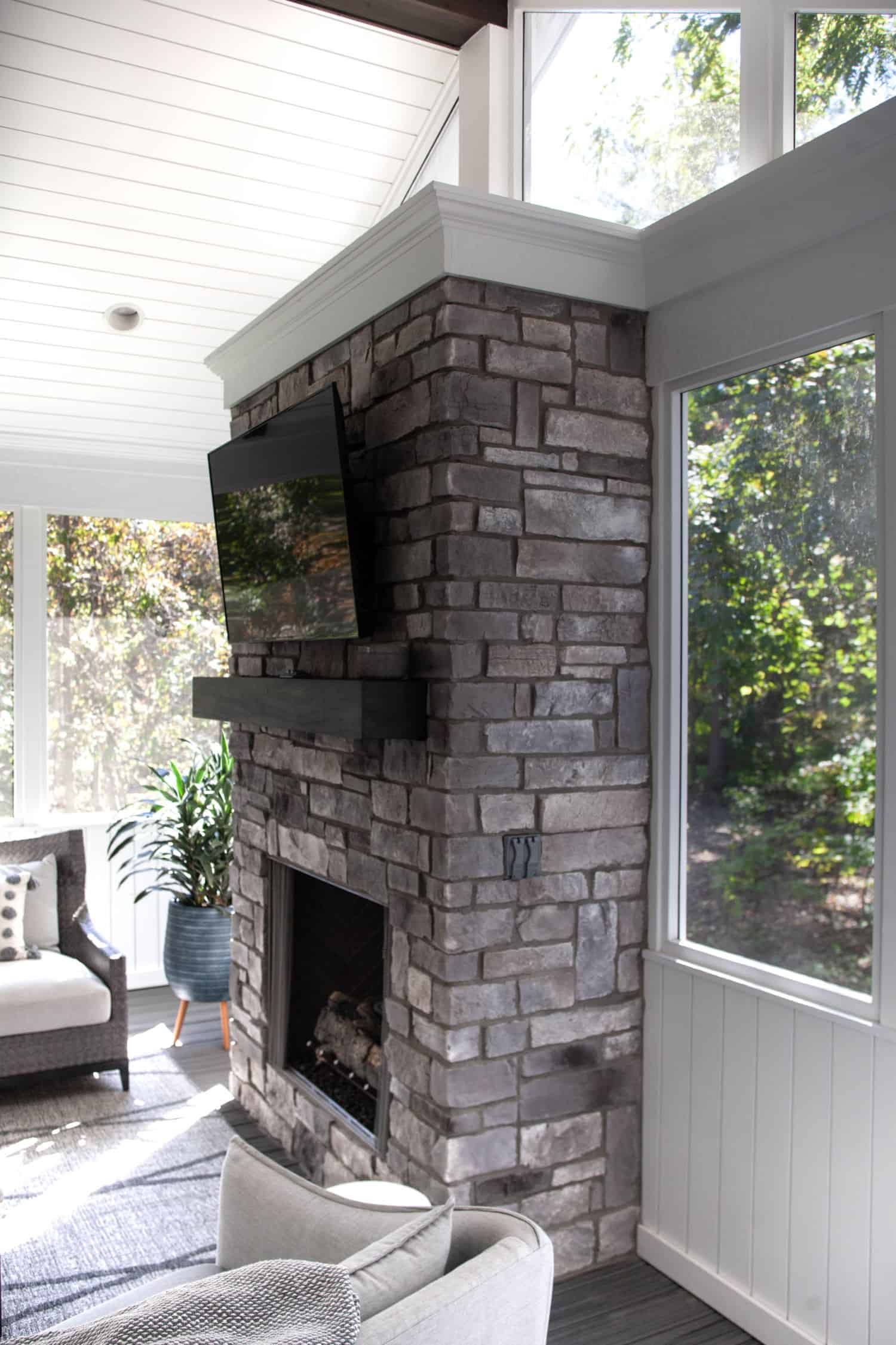 Nicholas Design Build | A living room with a stone fireplace and tv.