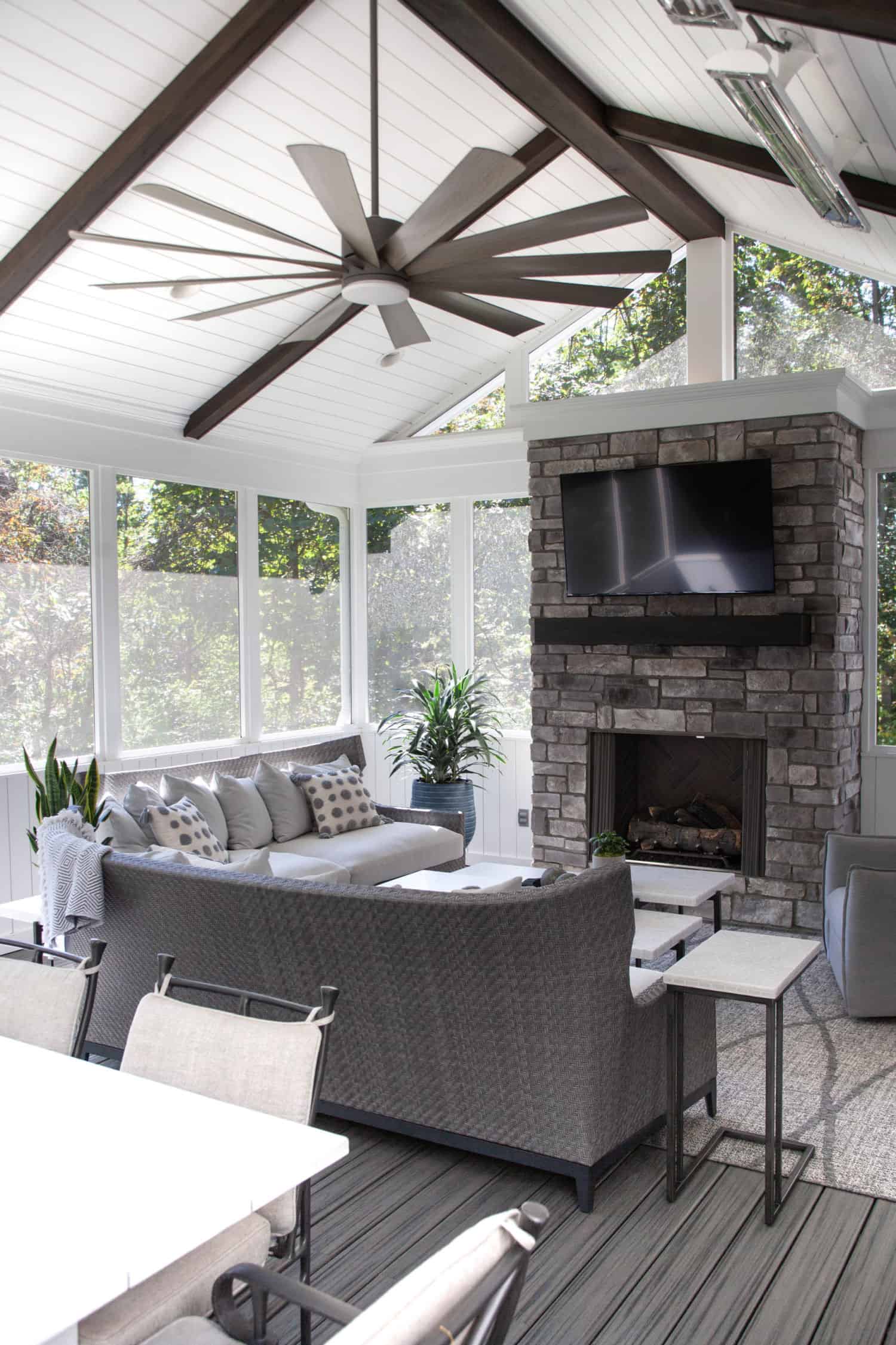 Nicholas Design Build | A screened in porch with a fireplace and tv.