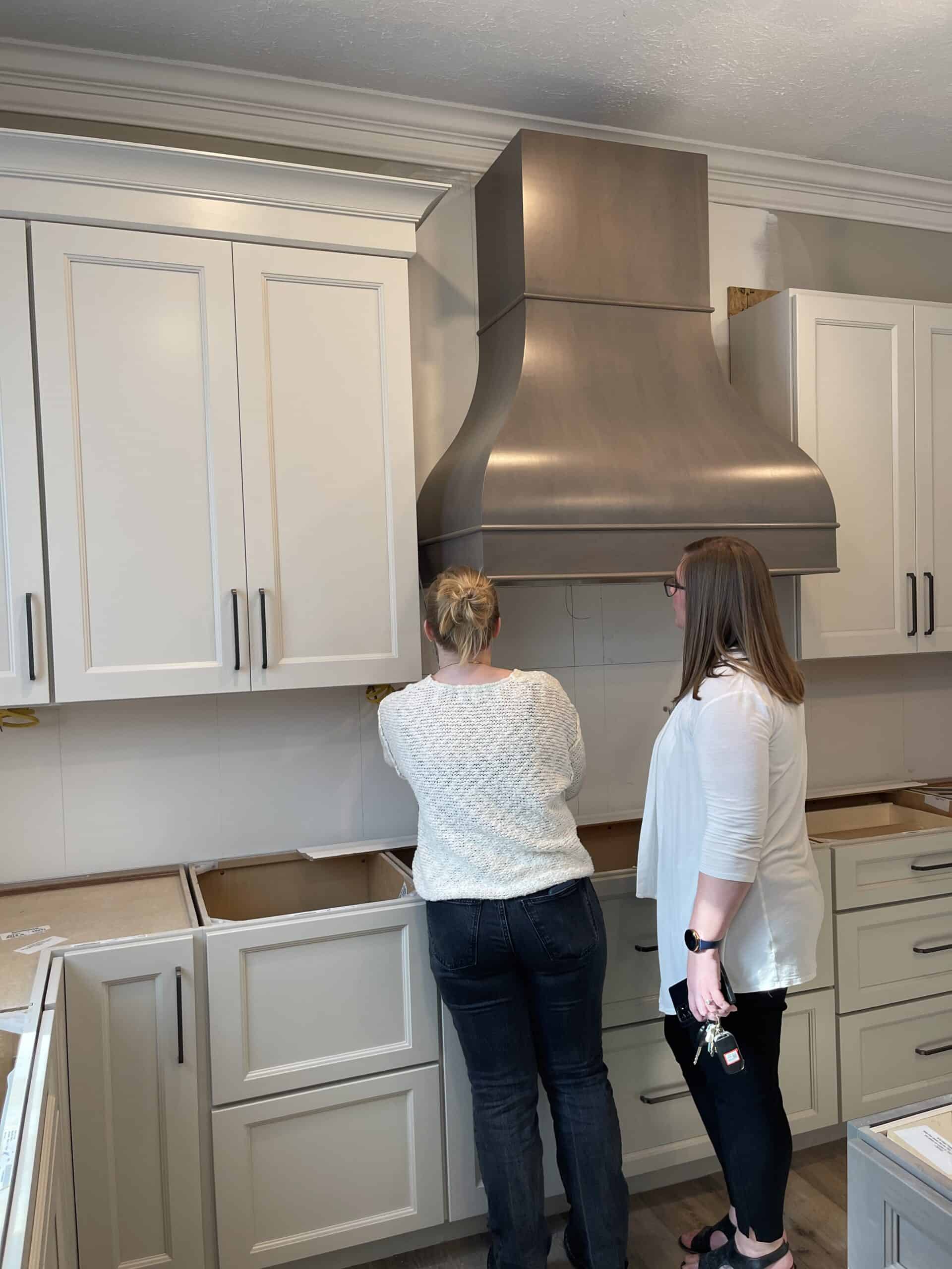 Nicholas Design Build | Two women standing in front of a kitchen with white cabinets.