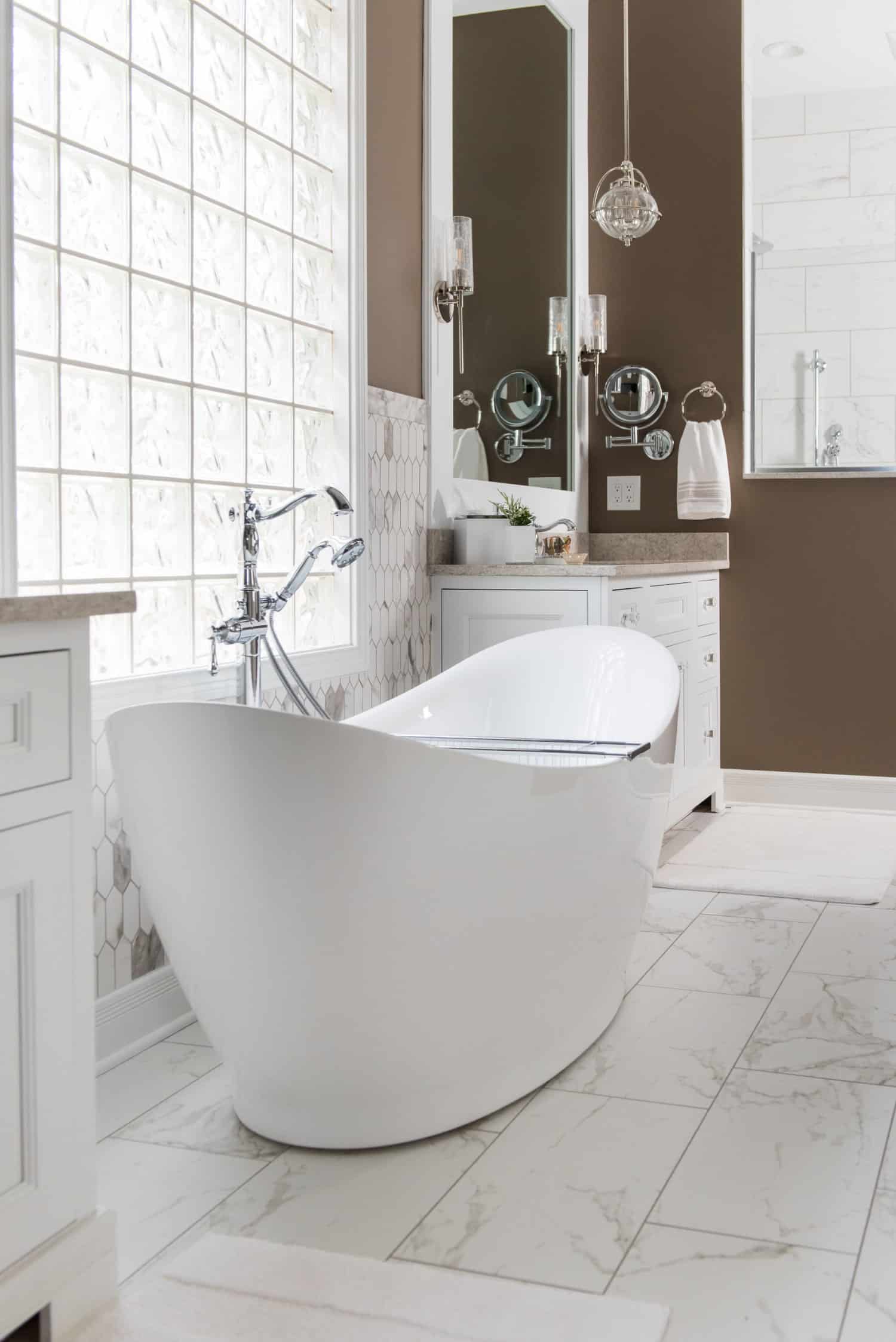 Nicholas Design Build | Transform your bathroom into a serene oasis with a white bathtub surrounded by warm brown walls.