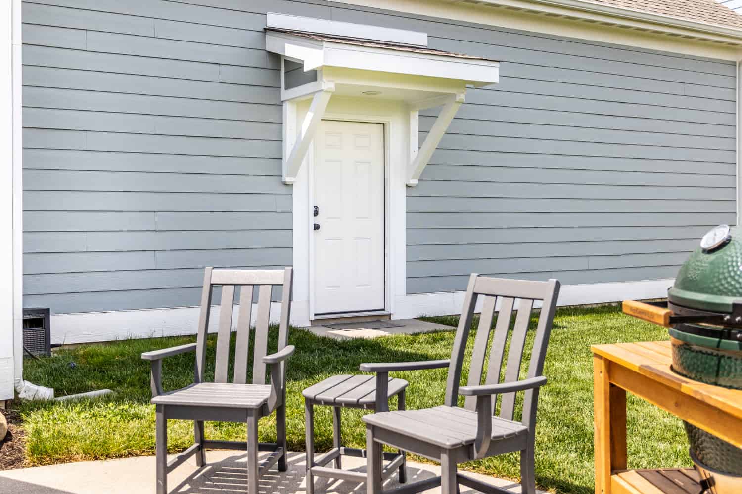 Nicholas Design Build | An outdoor grill and two chairs on a patio.