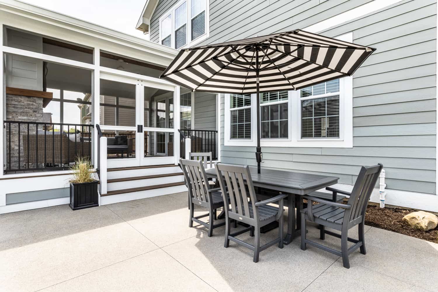 Nicholas Design Build | A remodeled patio with a table and chairs and an umbrella.