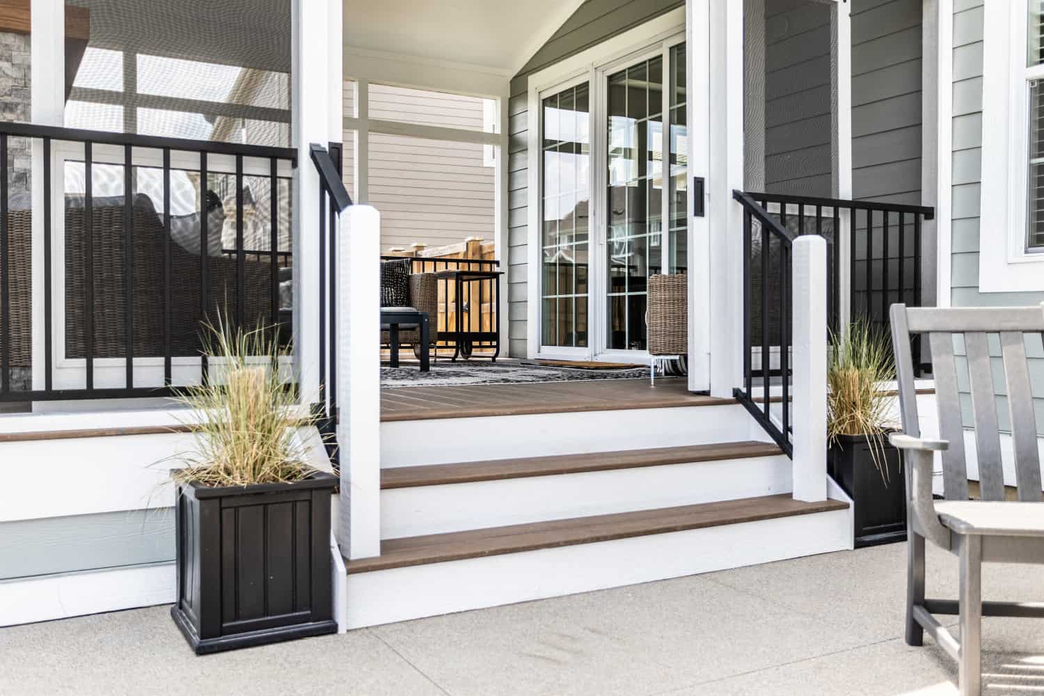 Nicholas Design Build | Remodel a porch with black furniture and a white railing.