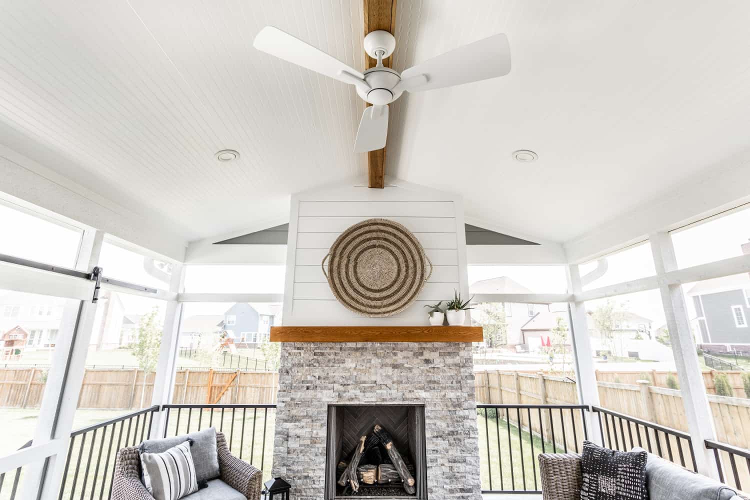 Nicholas Design Build | Remodel: A renovated screened in porch with a fireplace and a fan.