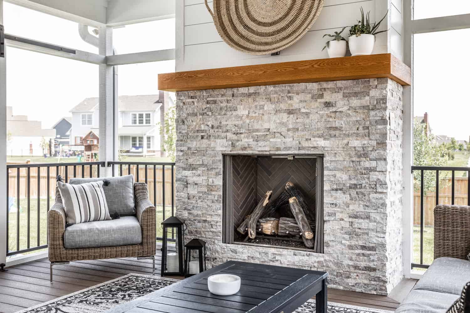 Nicholas Design Build | Remodel: A refurbished patio with a stone fireplace and wicker furniture.