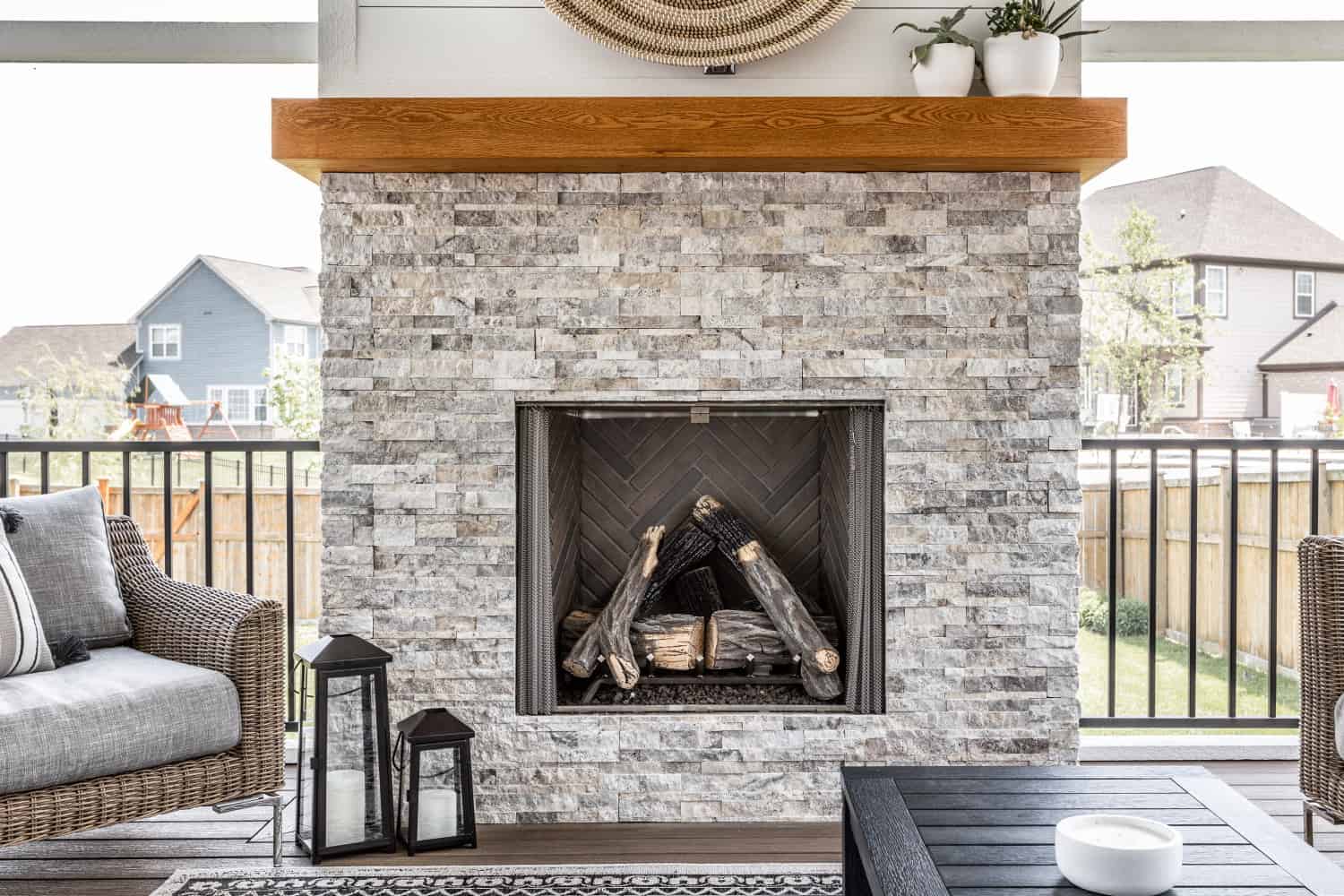 Nicholas Design Build | A remodeled patio with a fireplace and wicker furniture.