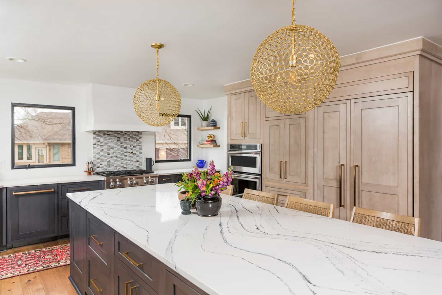 Nicholas Design Build | A remodeled kitchen with marble counter tops and gold pendant lights.