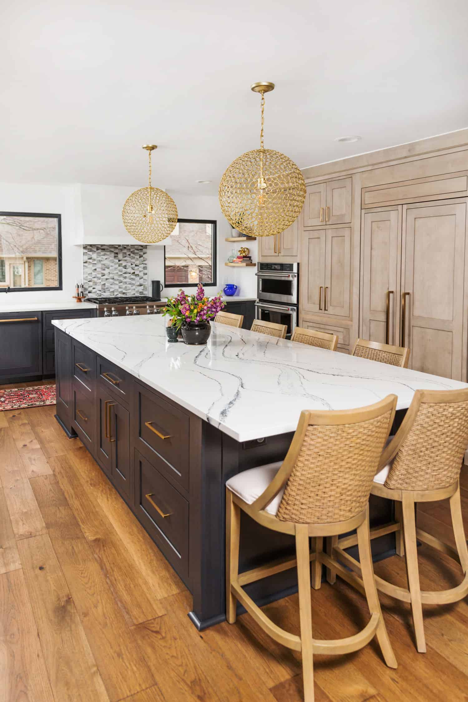 Nicholas Design Build | A remodeled kitchen with a marble island and wooden floors.