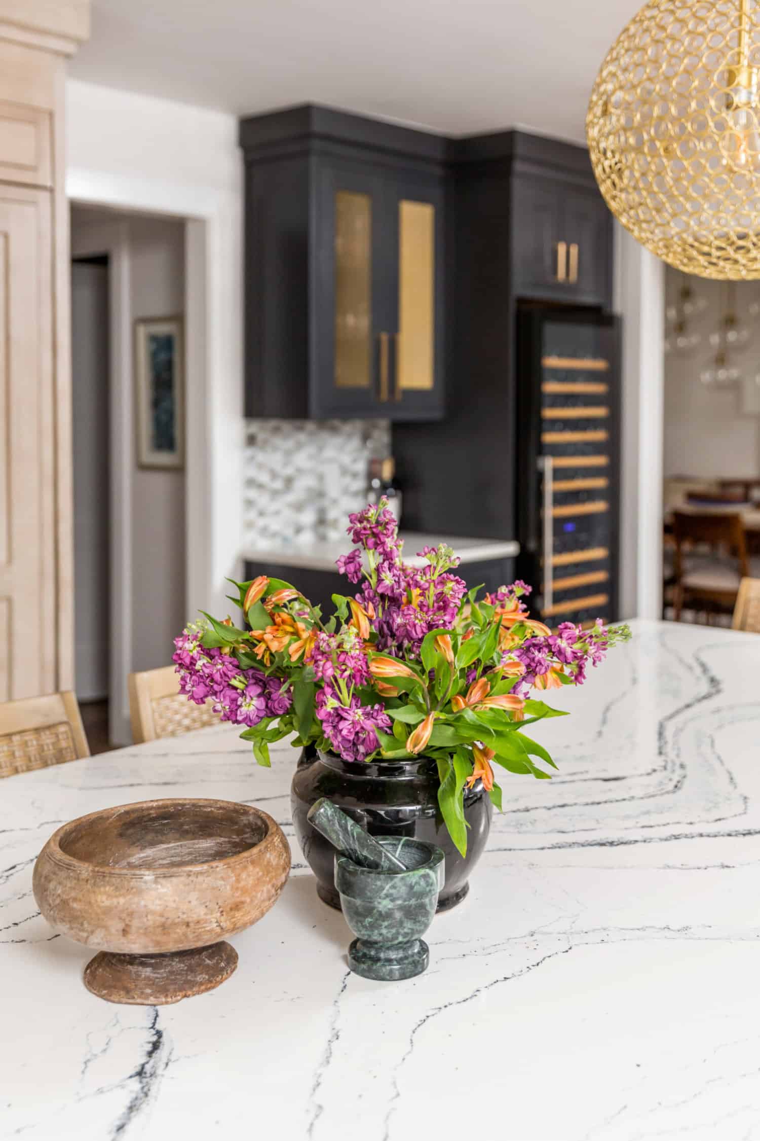 Nicholas Design Build | A remodeled kitchen with a marble counter top and a vase of flowers.