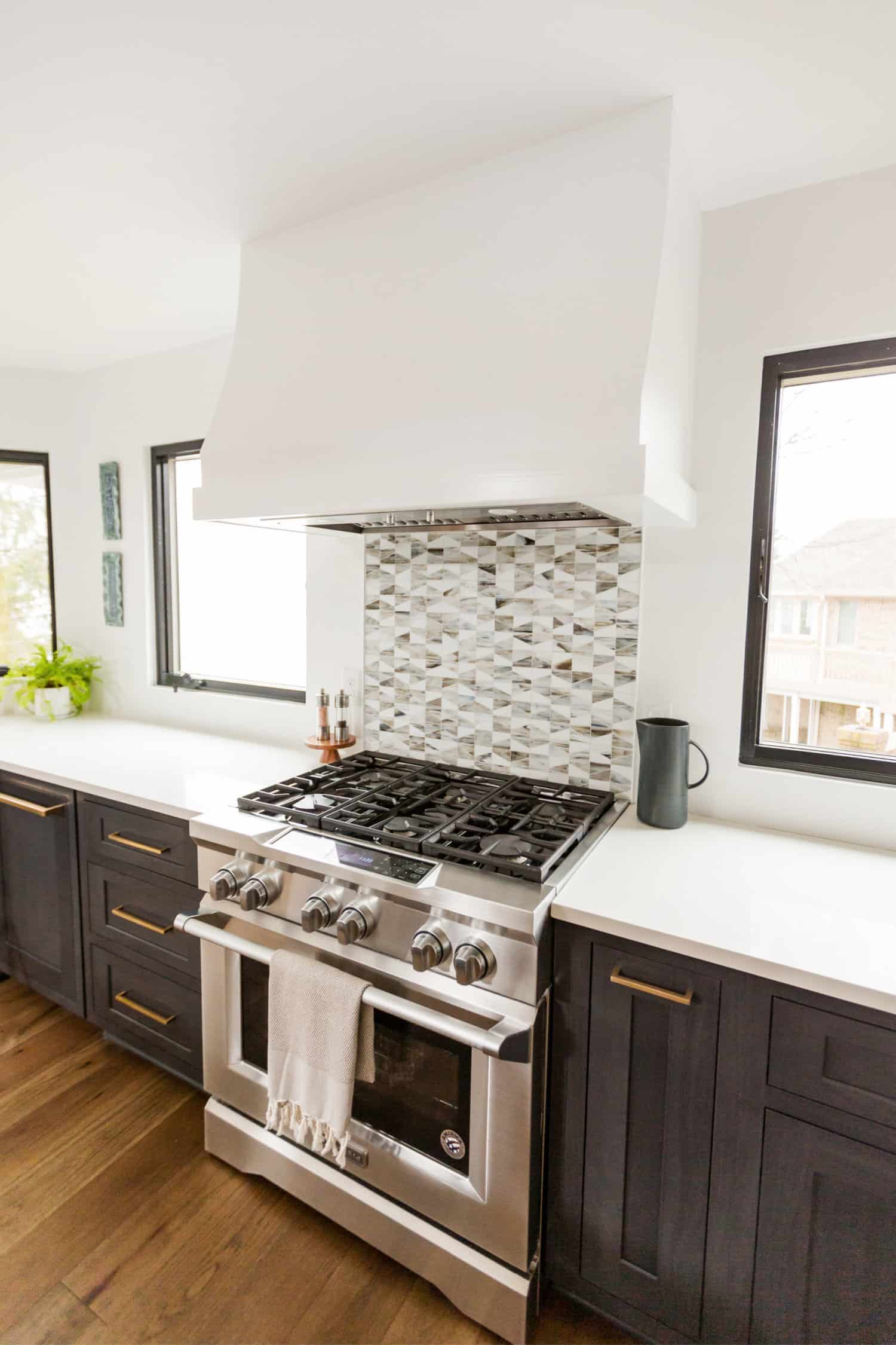 Nicholas Design Build | A remodeled kitchen with a stainless steel stove and white cabinets.