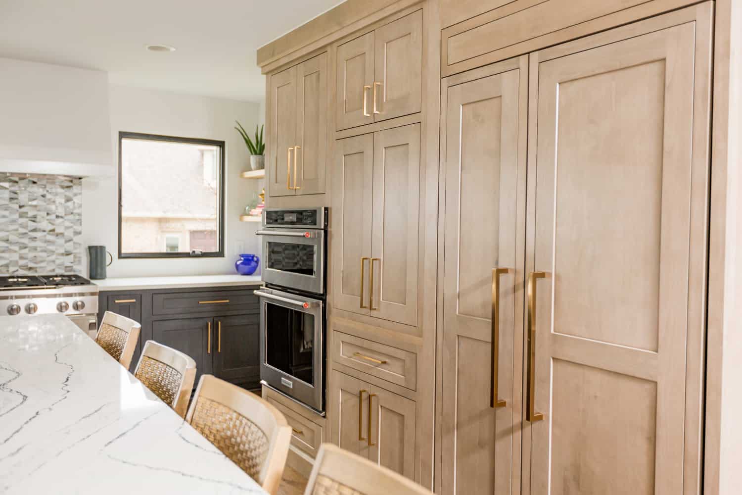 Nicholas Design Build | A remodeled kitchen with wooden cabinets and marble counter tops.