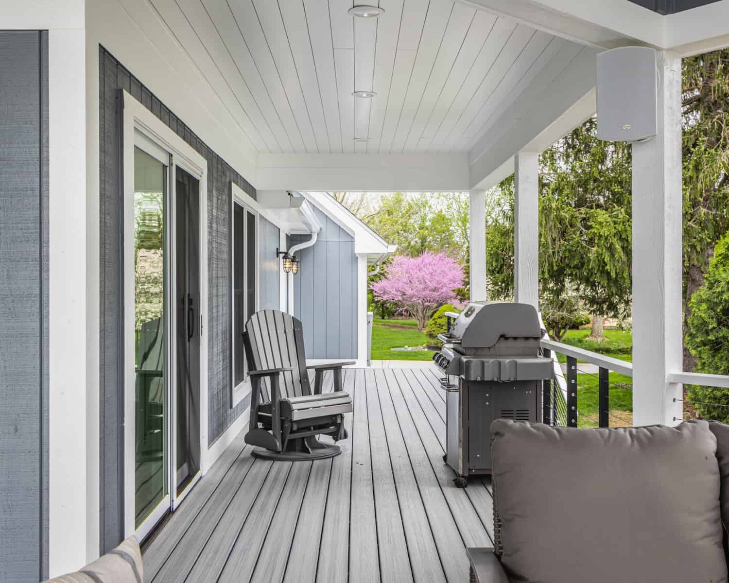 Nicholas Design Build | A gray porch with a rocking chair and a grill undergoing a remodel.