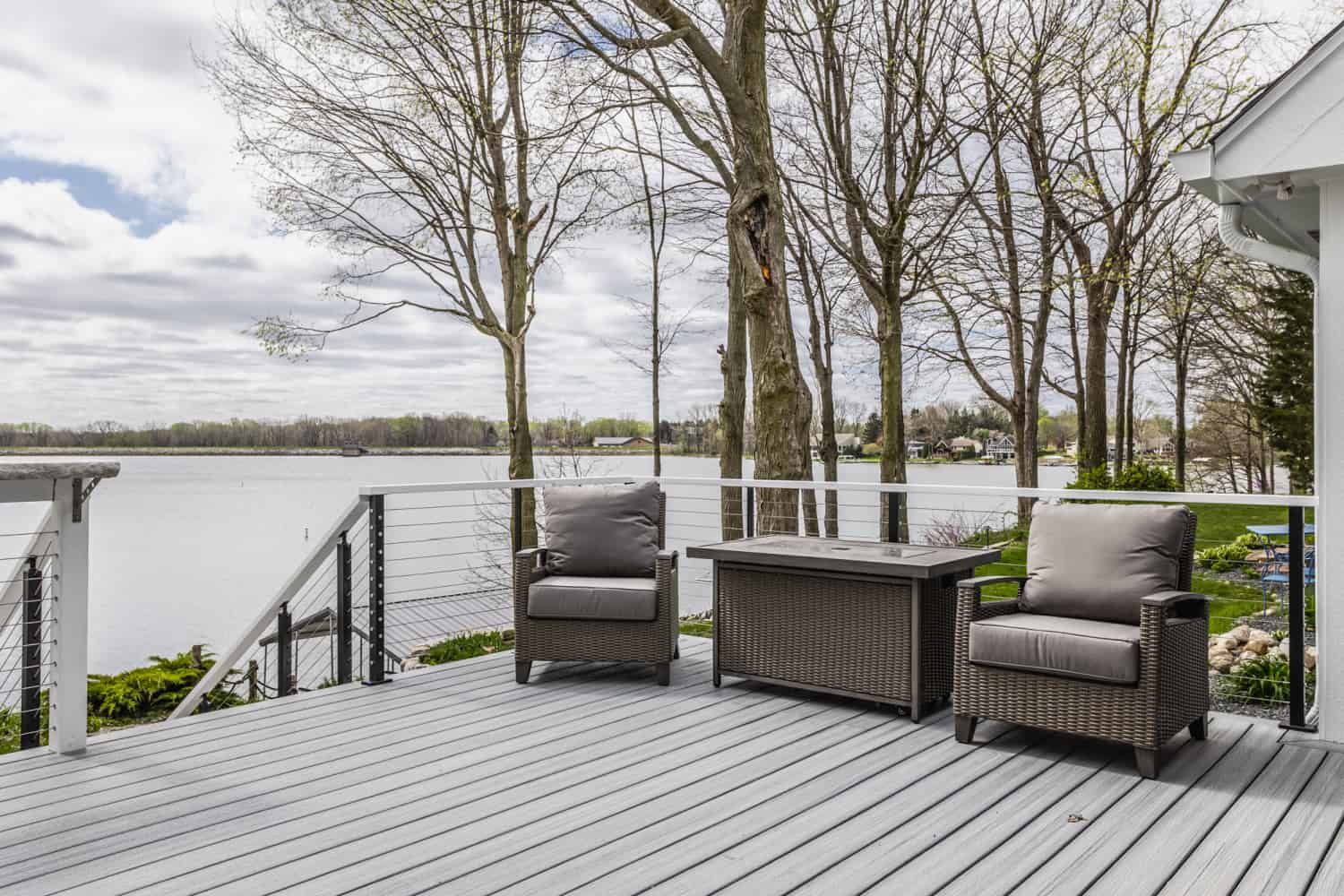Nicholas Design Build | A deck with wicker furniture and a view of a lake, perfect for a remodel.