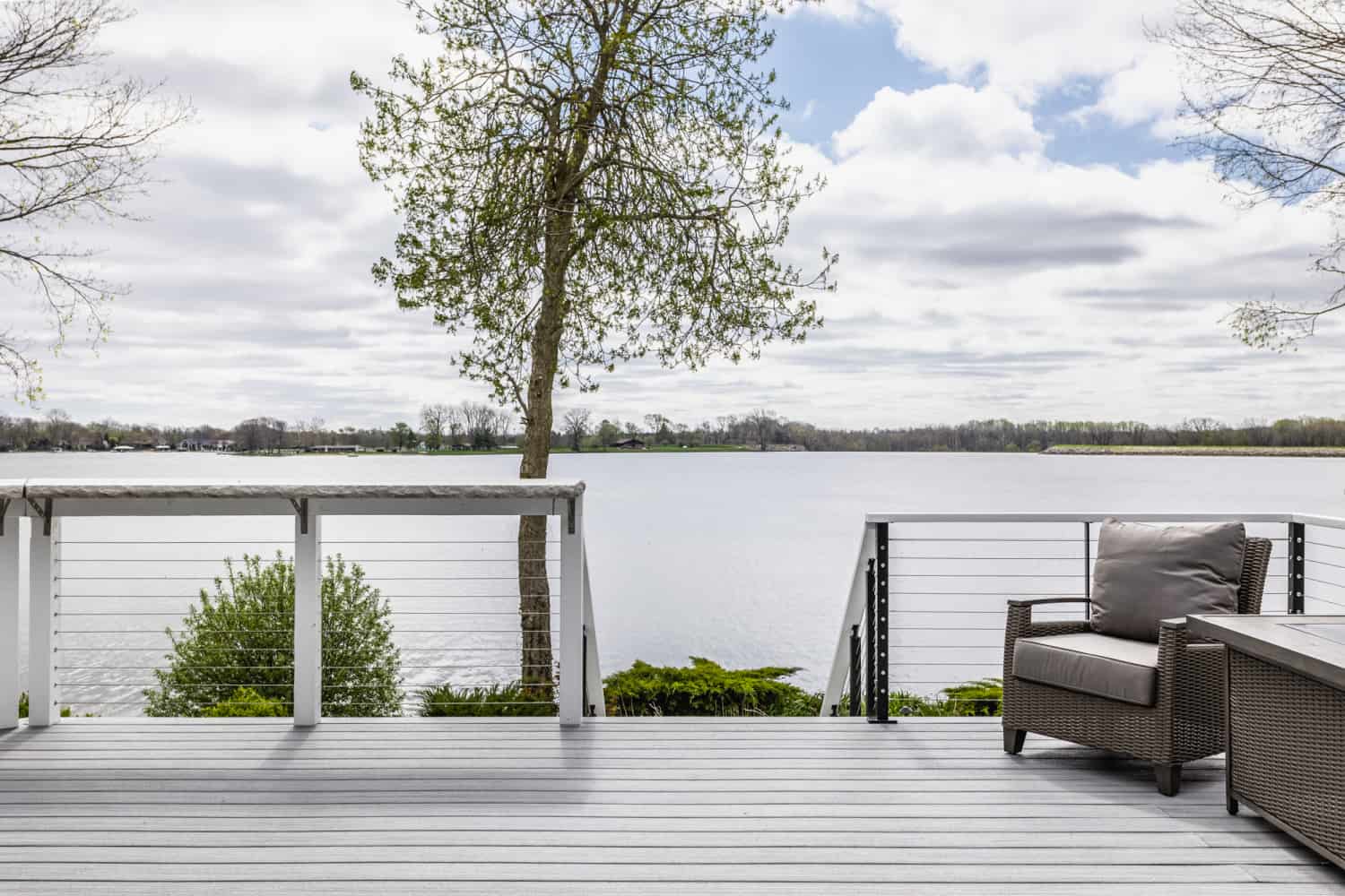 Nicholas Design Build | A remodeled deck overlooking a lake with furniture.