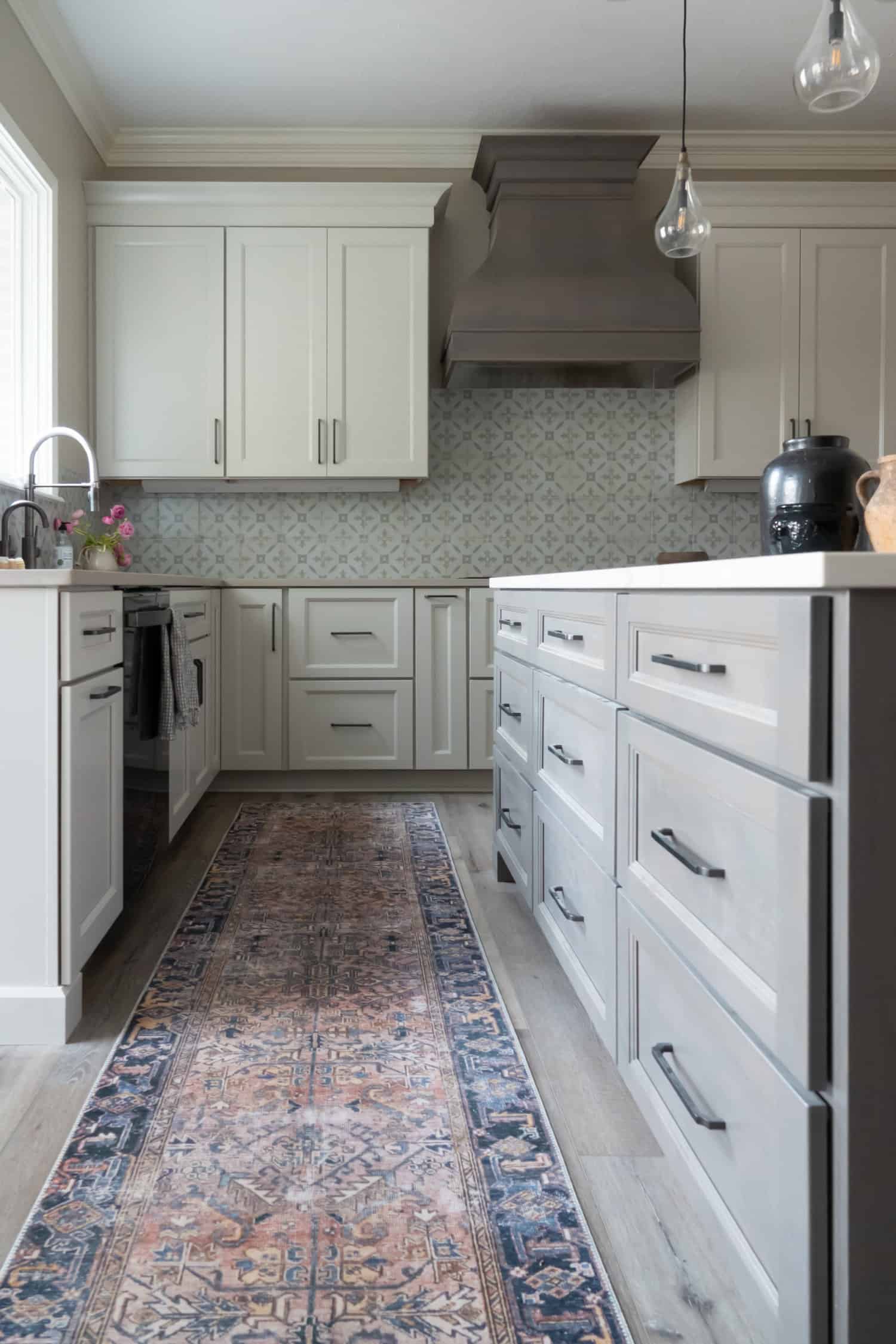 Nicholas Design Build | A remodeled kitchen with white cabinets and a rug on the floor.