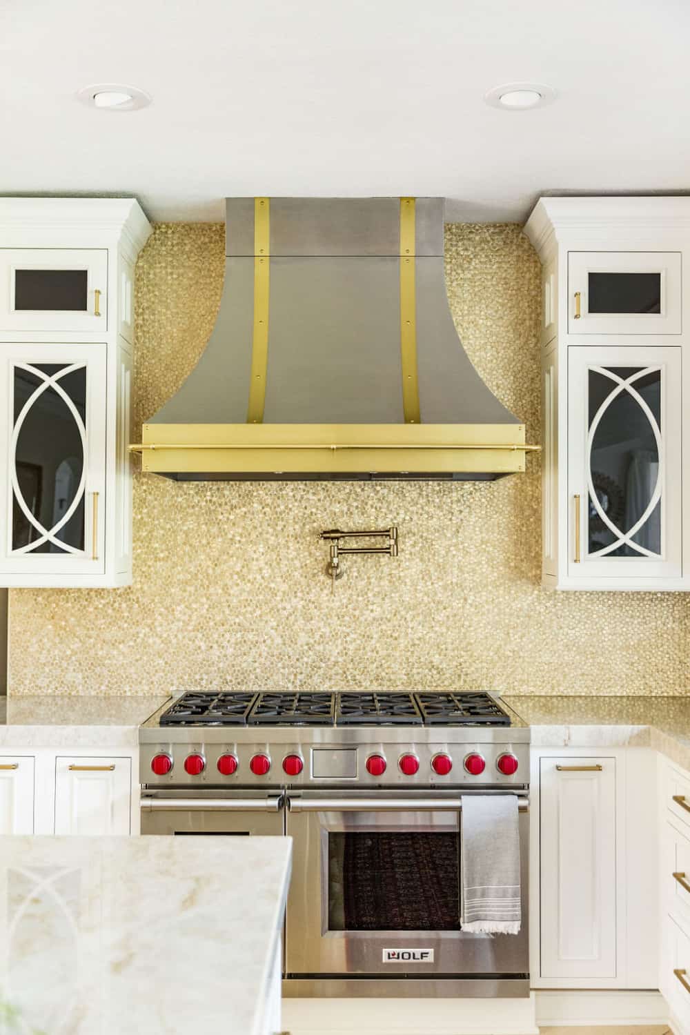 Nicholas Design Build | Remodel of a kitchen with white cabinets and a gold stove hood.