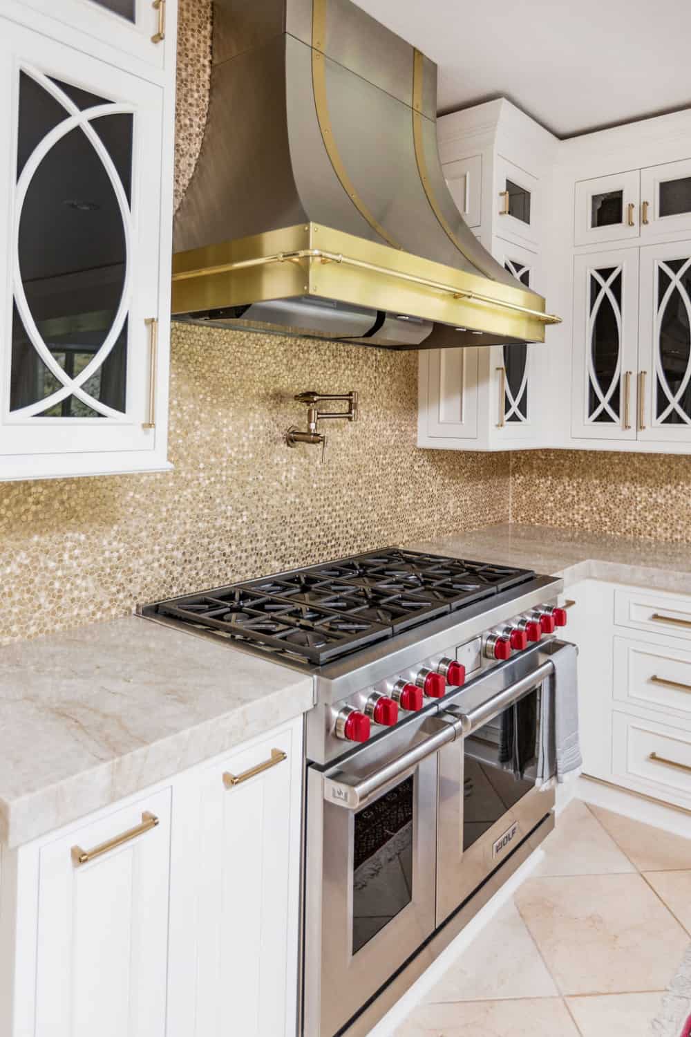 Nicholas Design Build | A remodeled kitchen with a white and gold color scheme, equipped with a stove and oven.