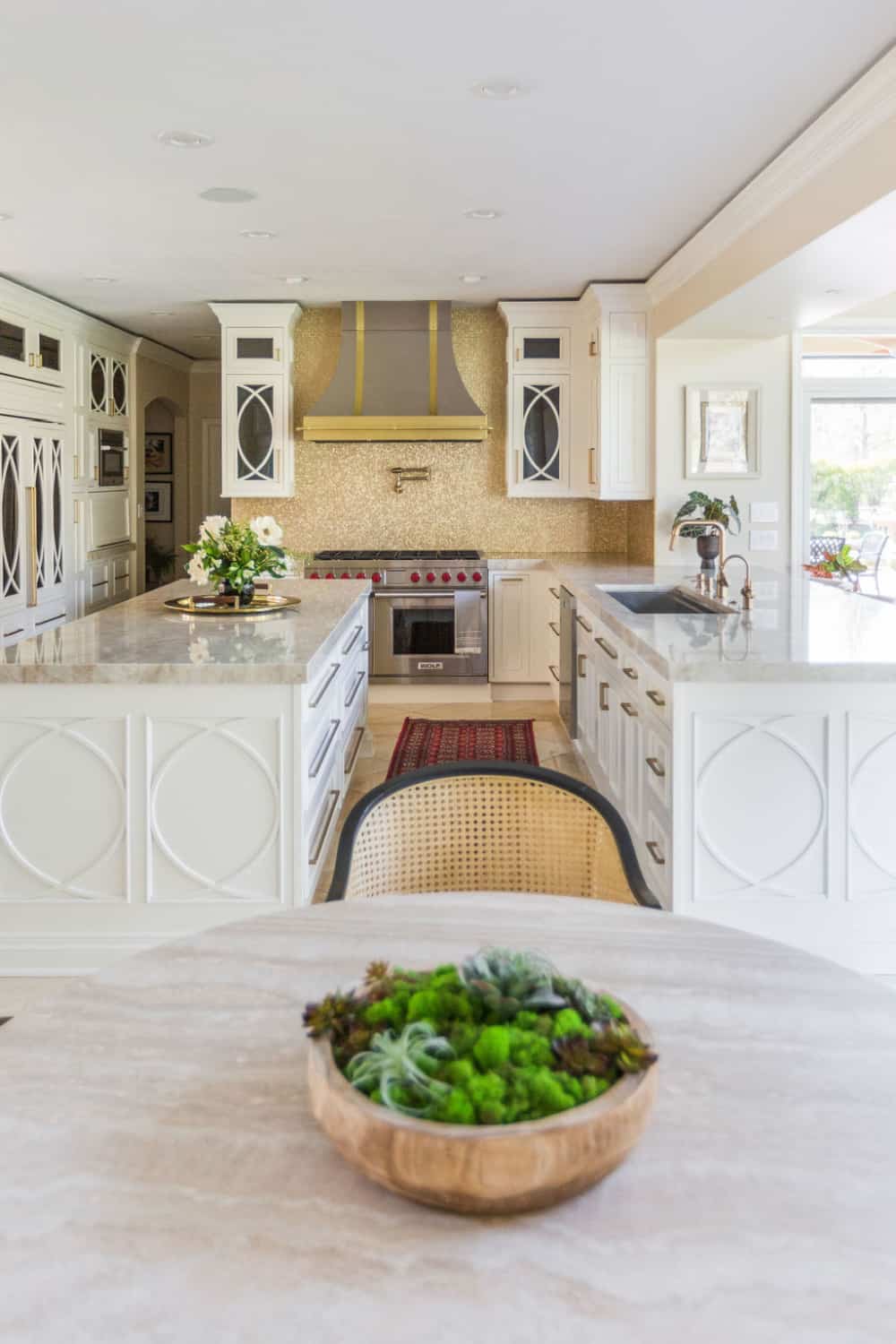 Nicholas Design Build | A large kitchen with white cabinets and marble counter tops undergoing a remodel.