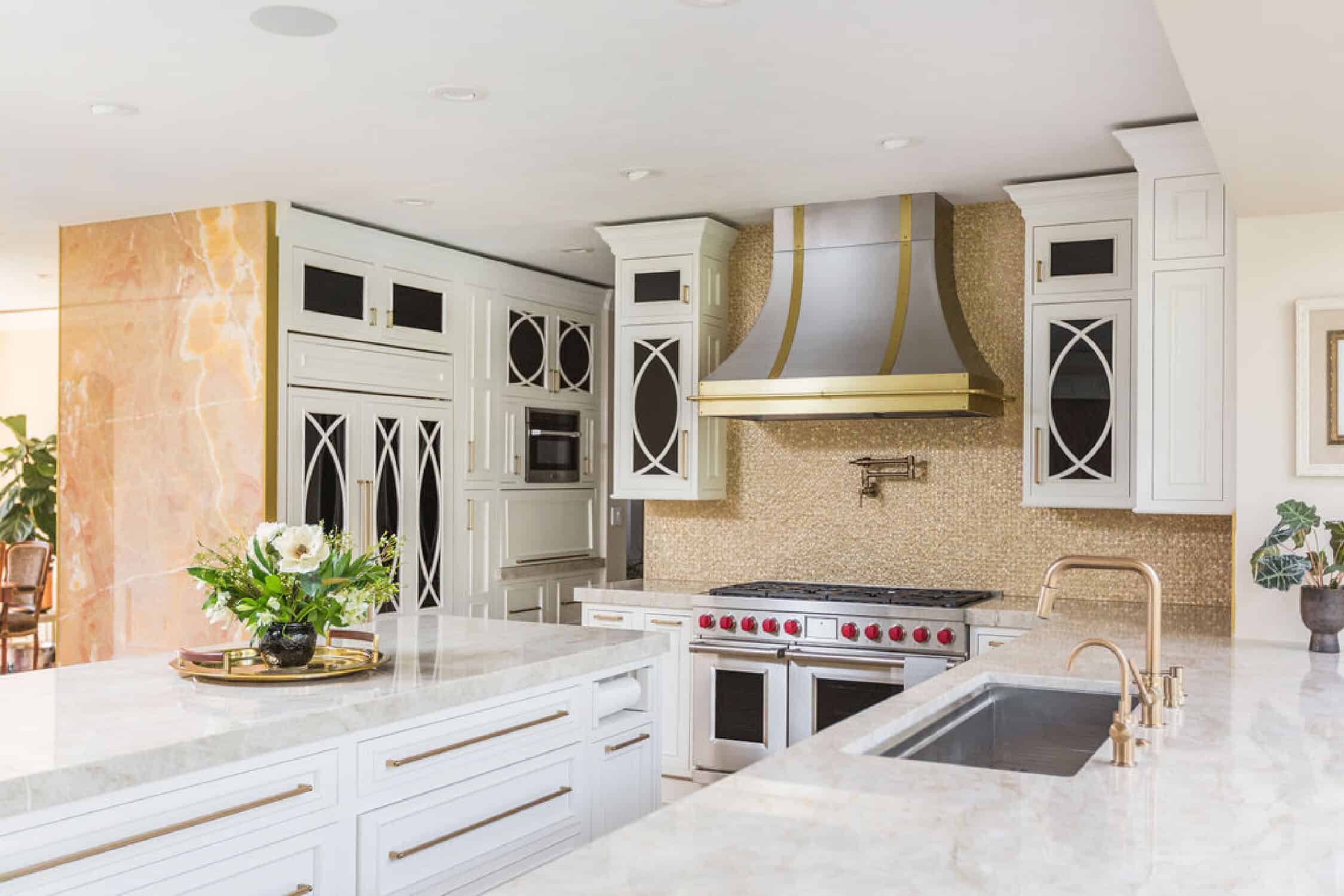 Nicholas Design Build | A white kitchen with marble counter tops undergoing a remodel, featuring a gold hood.