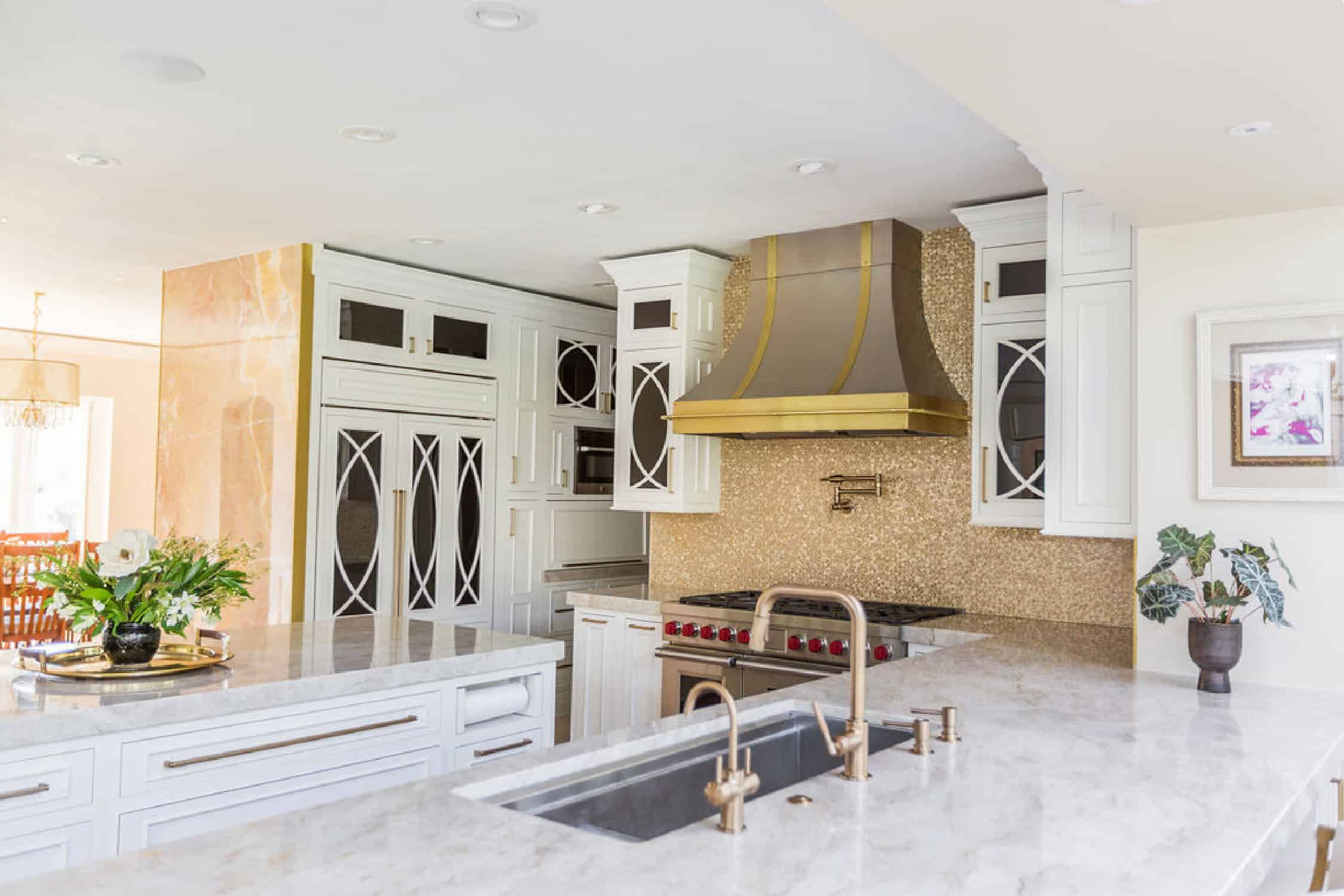 Nicholas Design Build | A remodelled kitchen with marble counter tops and a gold hood.