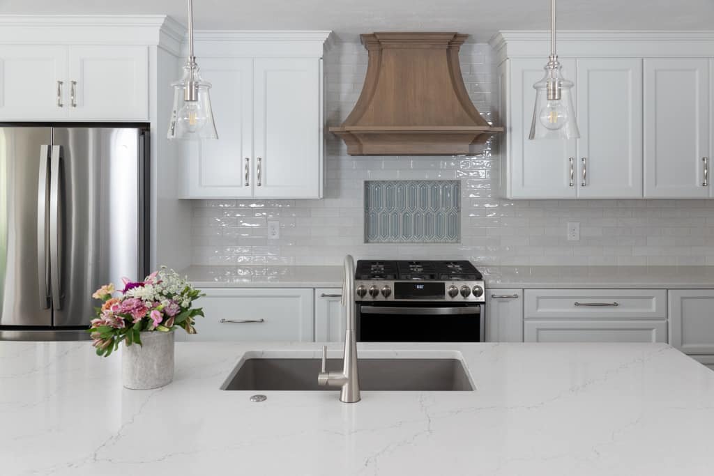Nicholas Design Build | A remodeled kitchen with white cabinets and marble counter tops.
