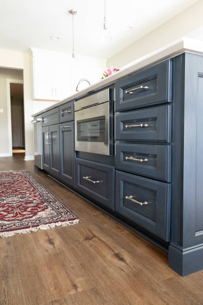 Nicholas Design Build | A remodeled kitchen with blue cabinets and a rug on the floor.