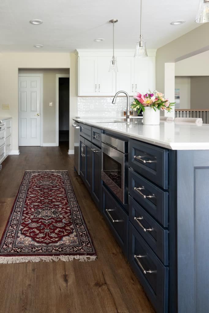 Nicholas Design Build | A remodeled kitchen with blue cabinets and a rug on the floor.
