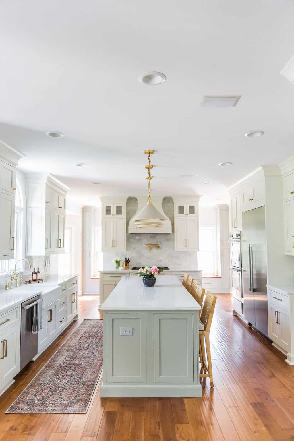 Nicholas Design Build | A white kitchen with a large island and hardwood floors, perfect for a remodel.