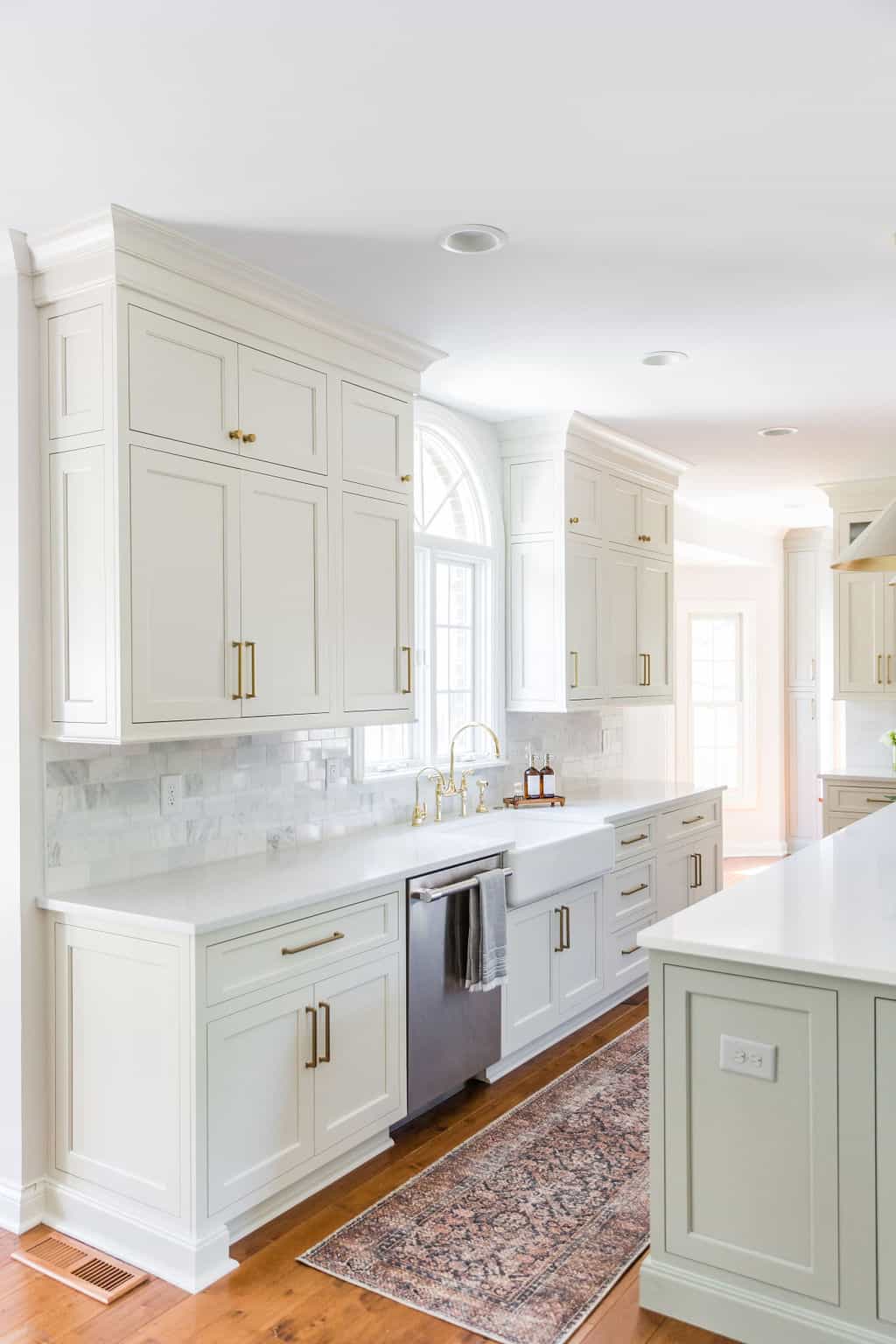 Nicholas Design Build | Remodel: A white kitchen with hardwood floors and a rug undergoing a renovation.